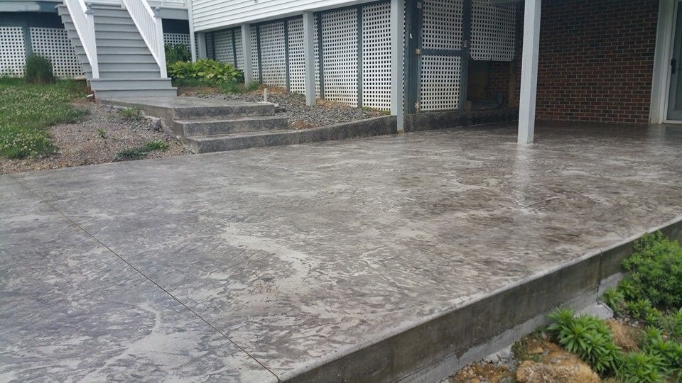 A concrete patio with stairs leading up to a house.