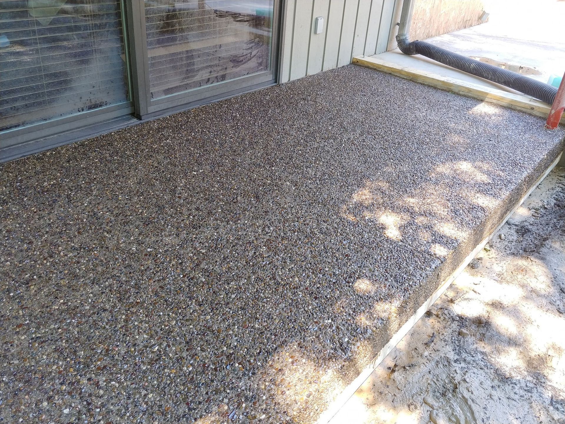 A patio with gravel and a ladder in front of a building.