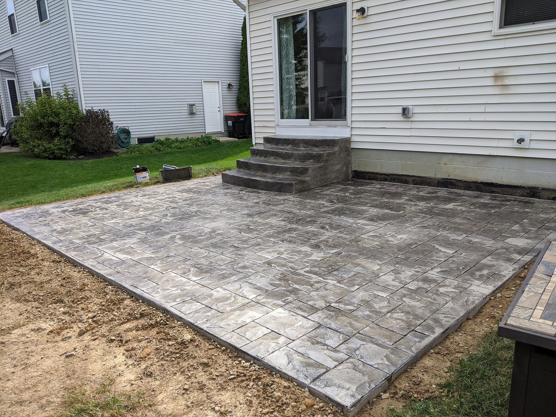 A patio with stairs is being built in front of a house.