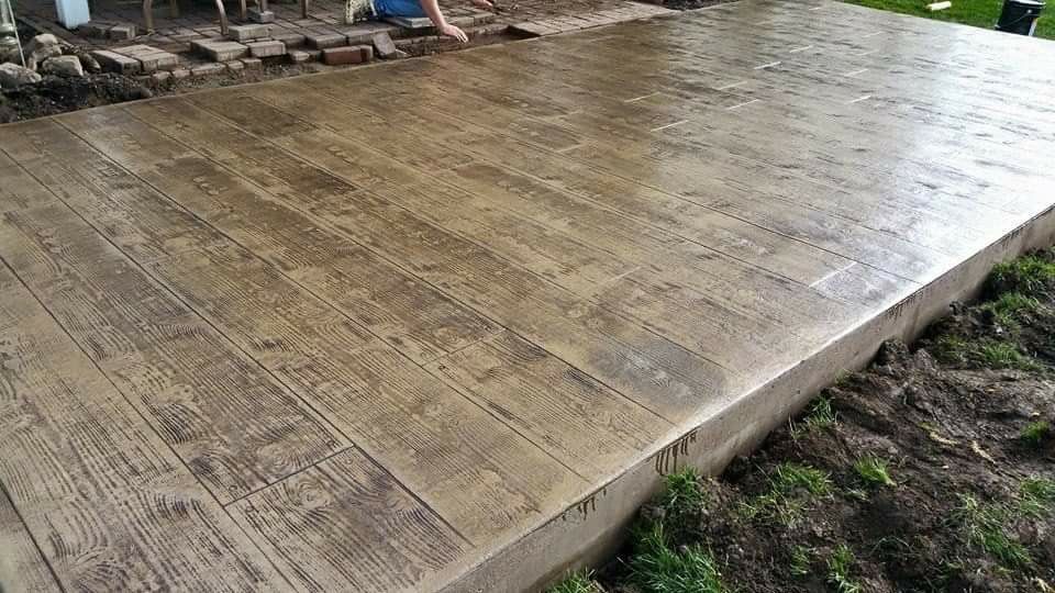 A person is painting a concrete floor that looks like wood.