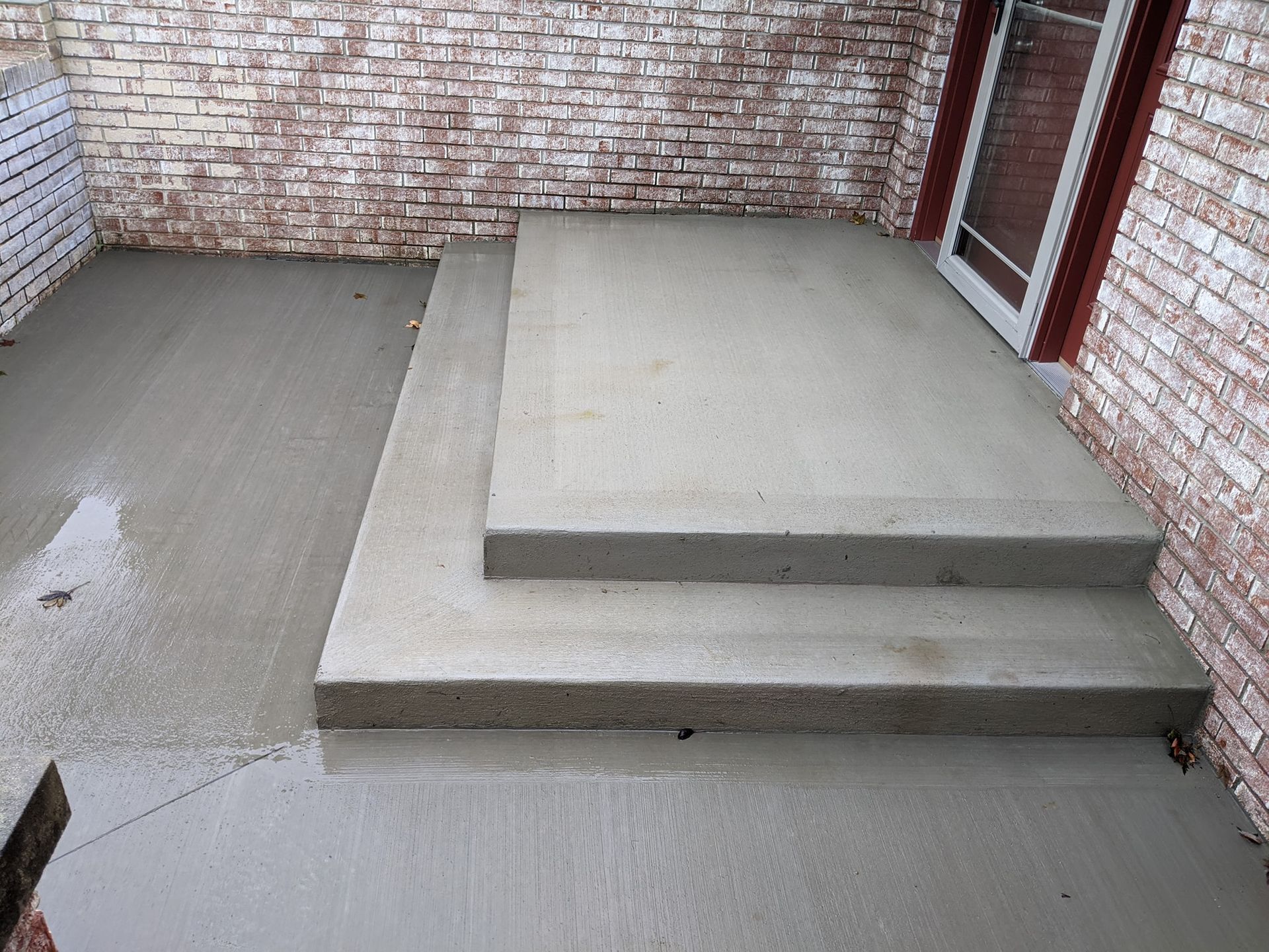 A porch with concrete steps and a brick wall