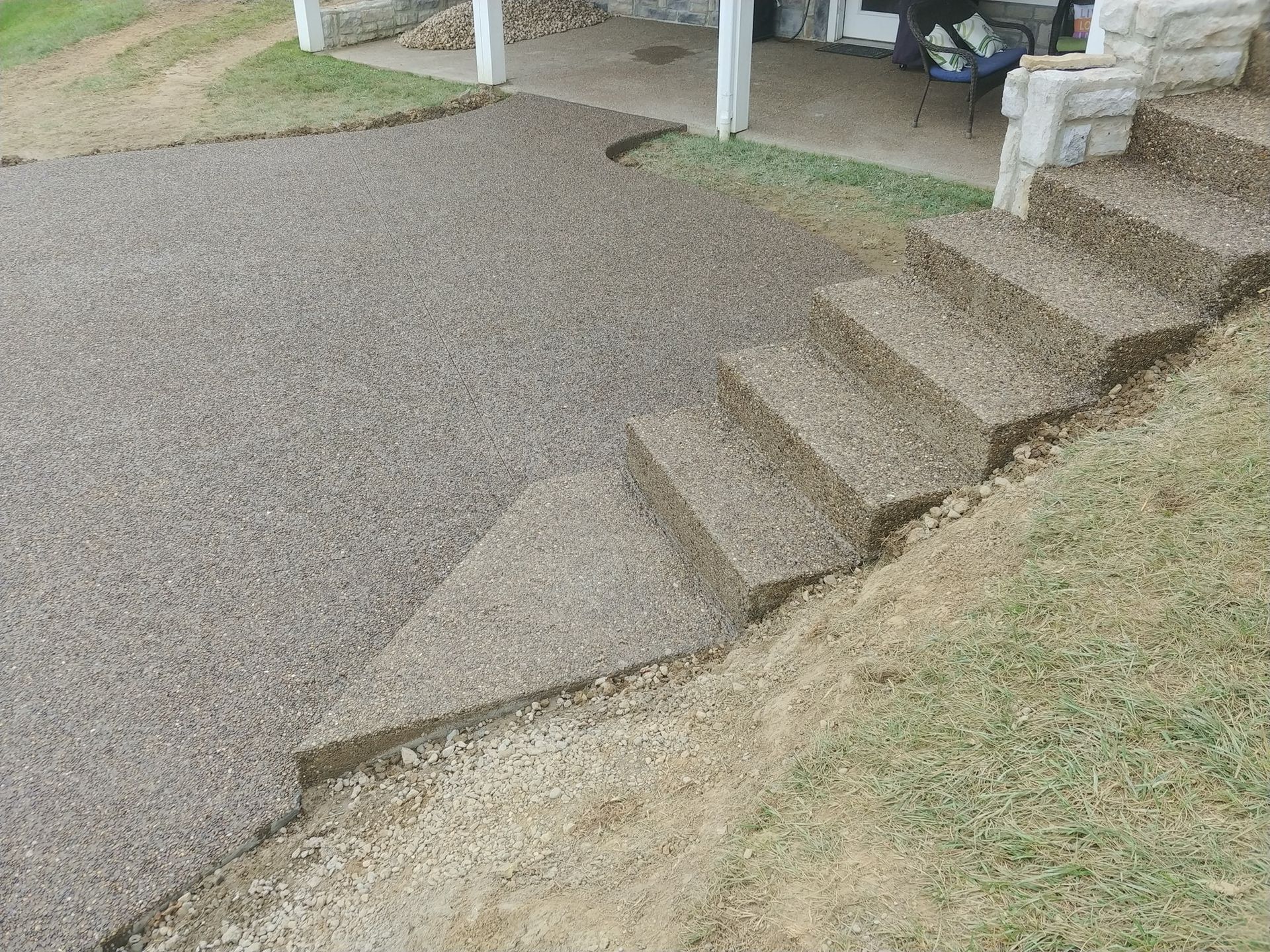 A concrete walkway with stairs leading up to a porch.