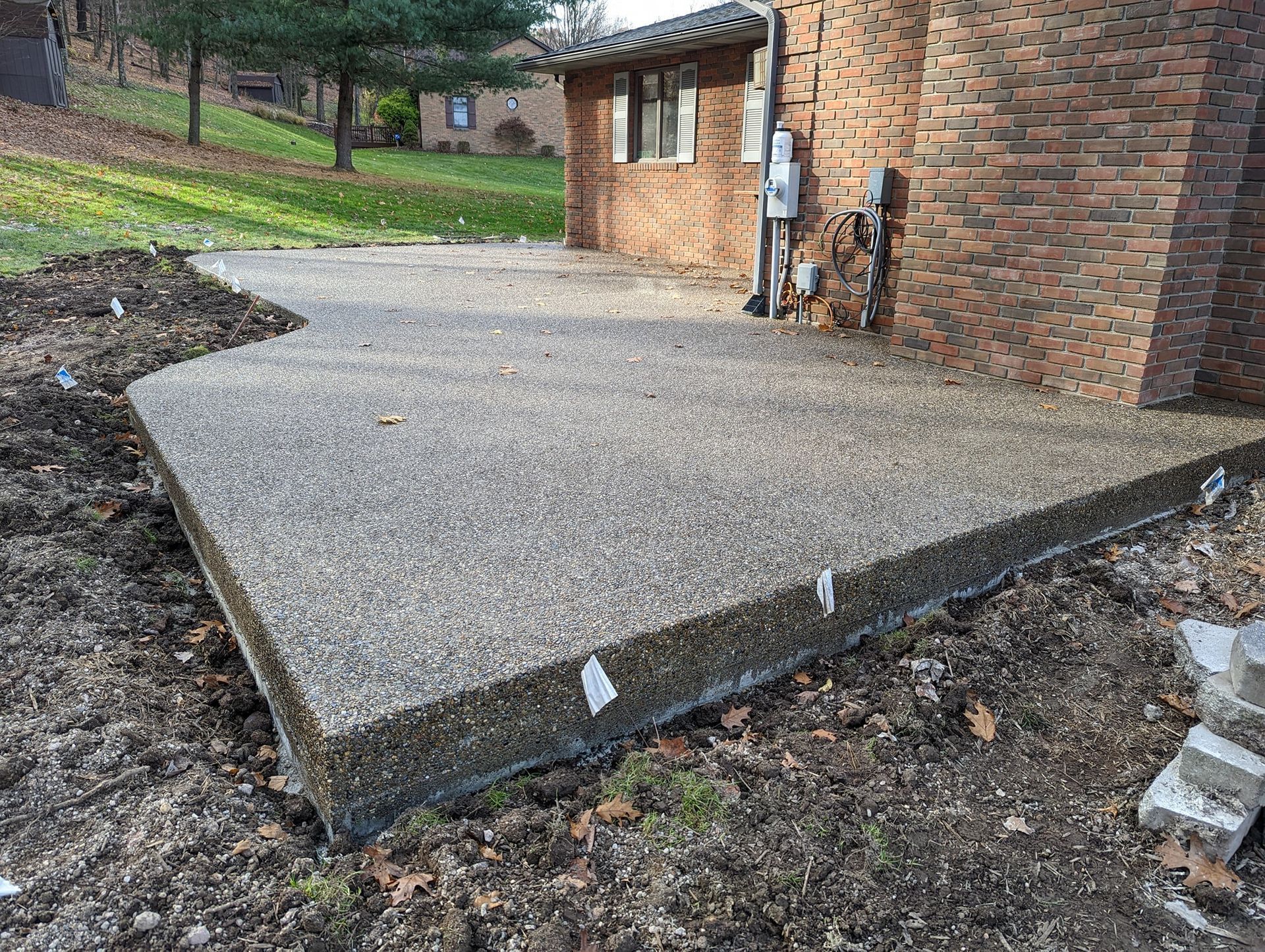 A concrete walkway is being built in front of a brick house.