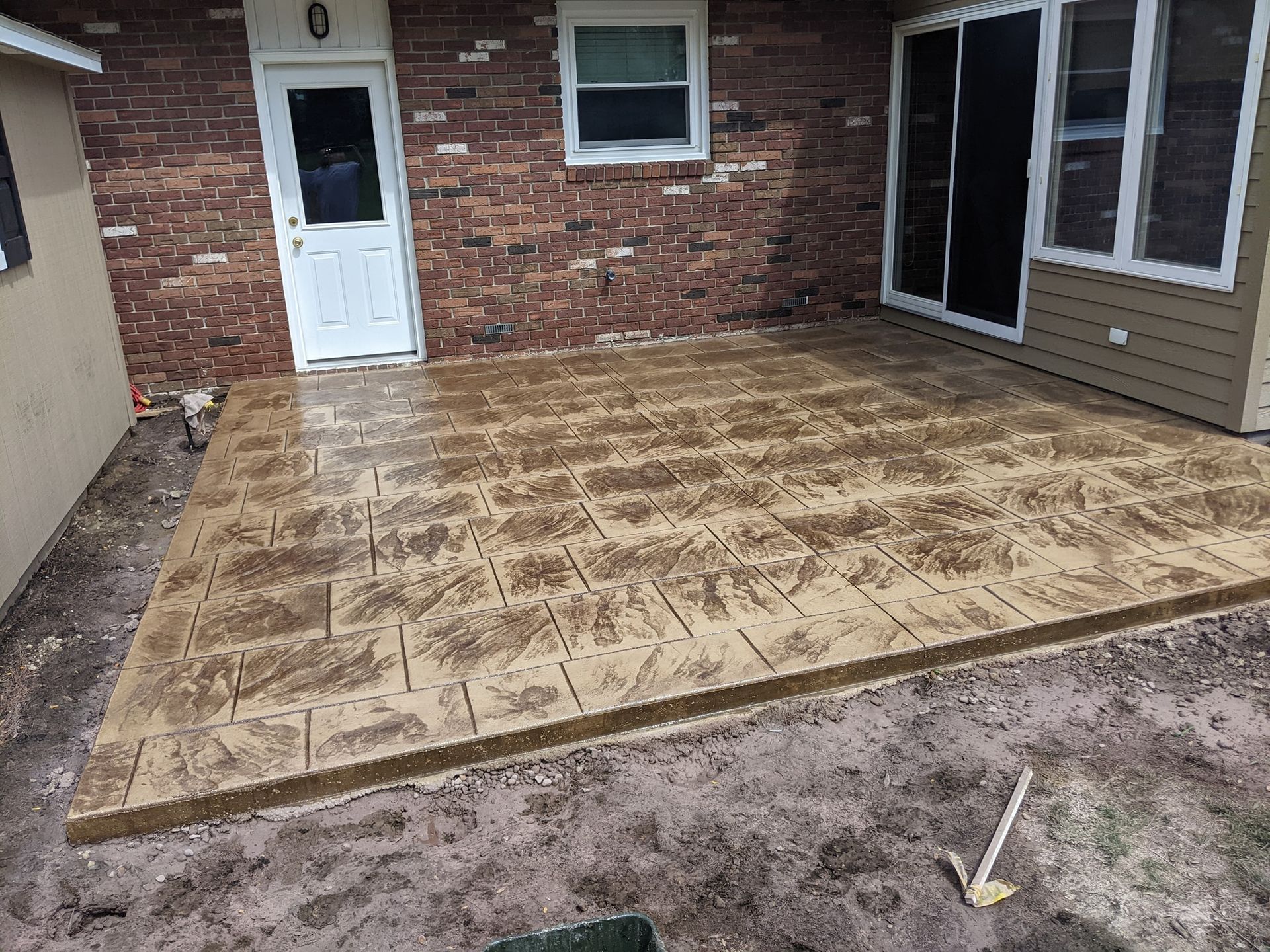 A patio is being built in front of a brick house.
