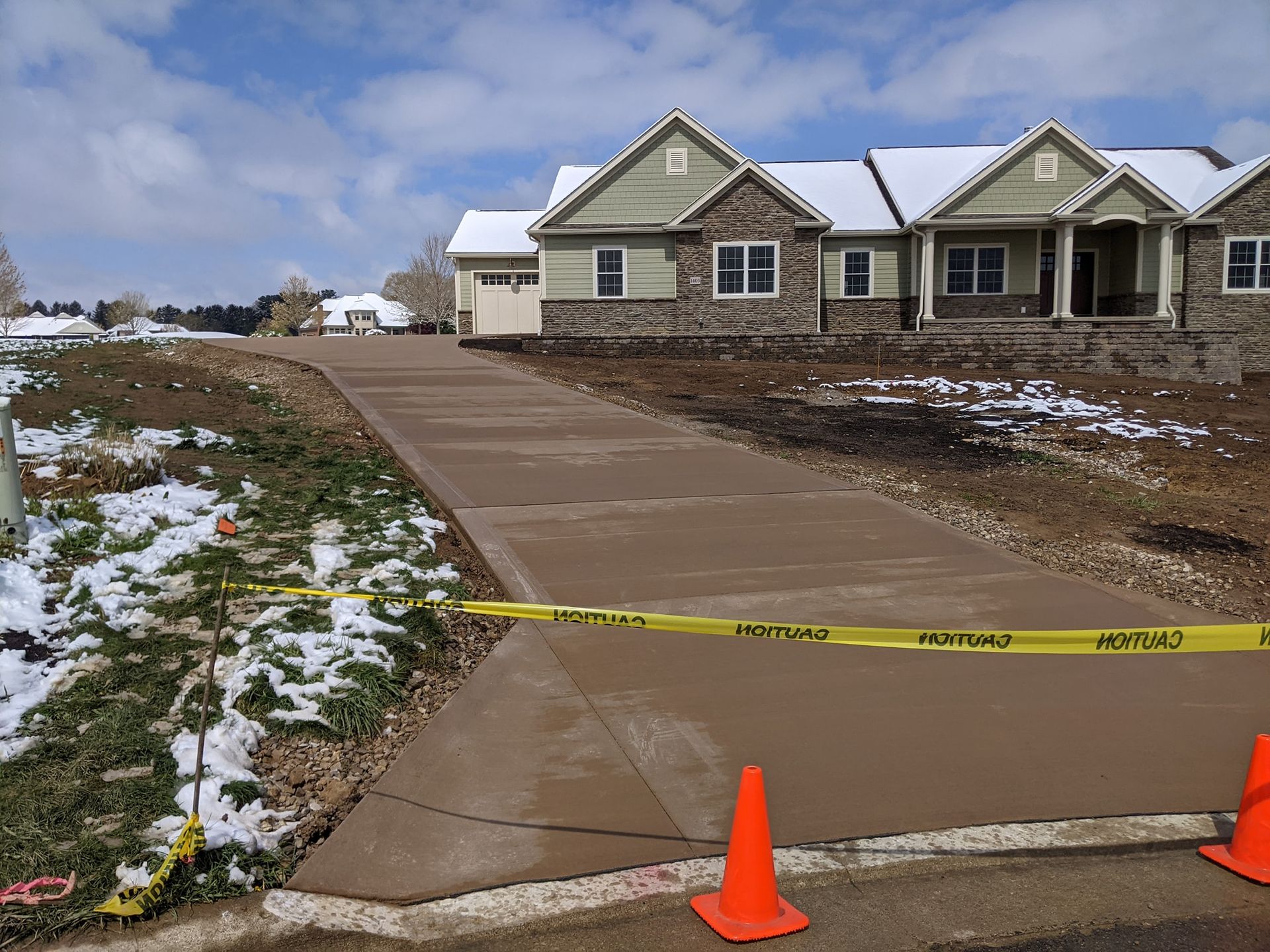 A concrete walkway leading to a house with snow on the ground
