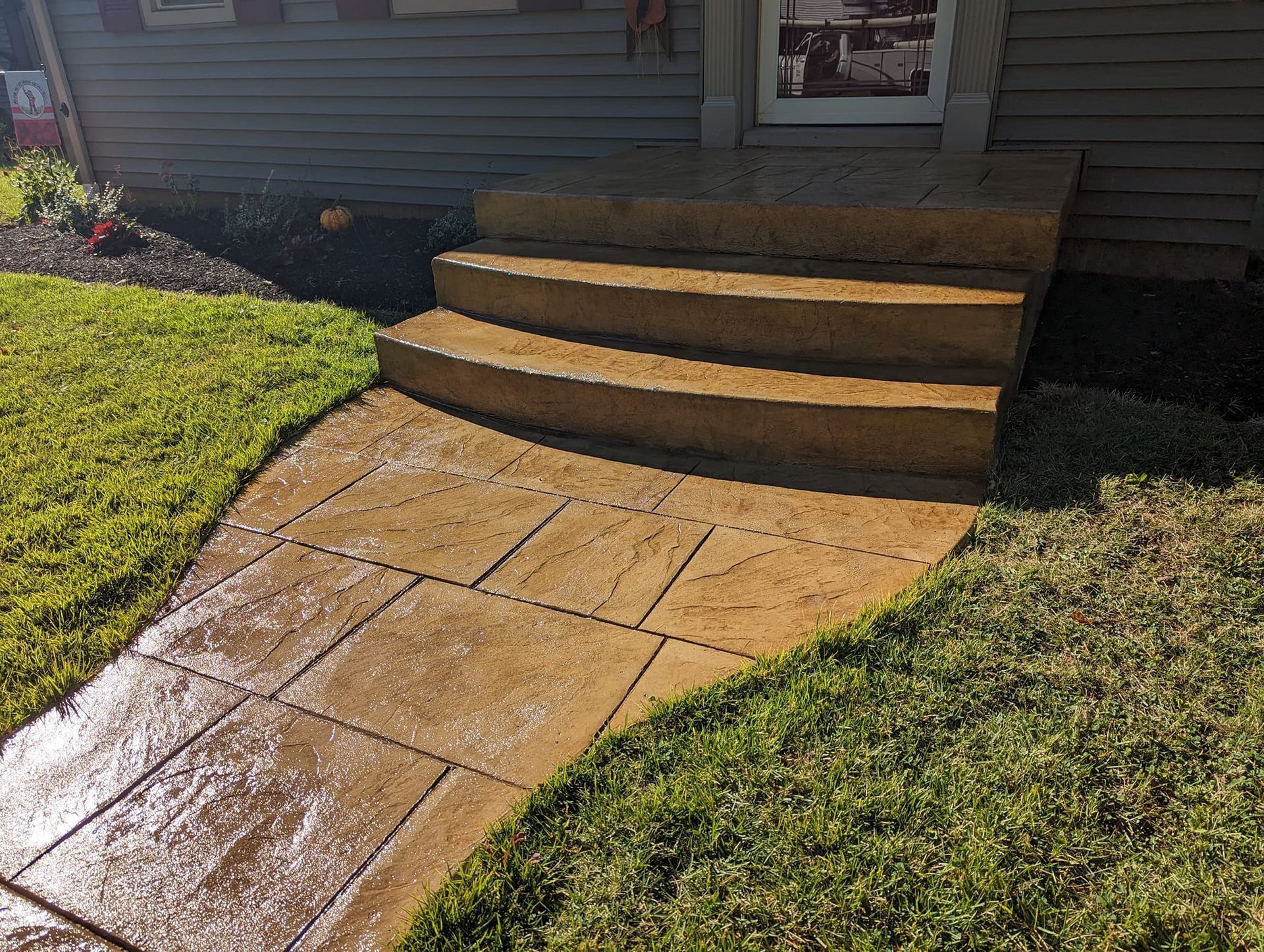 A concrete walkway leading to the front door of a house.