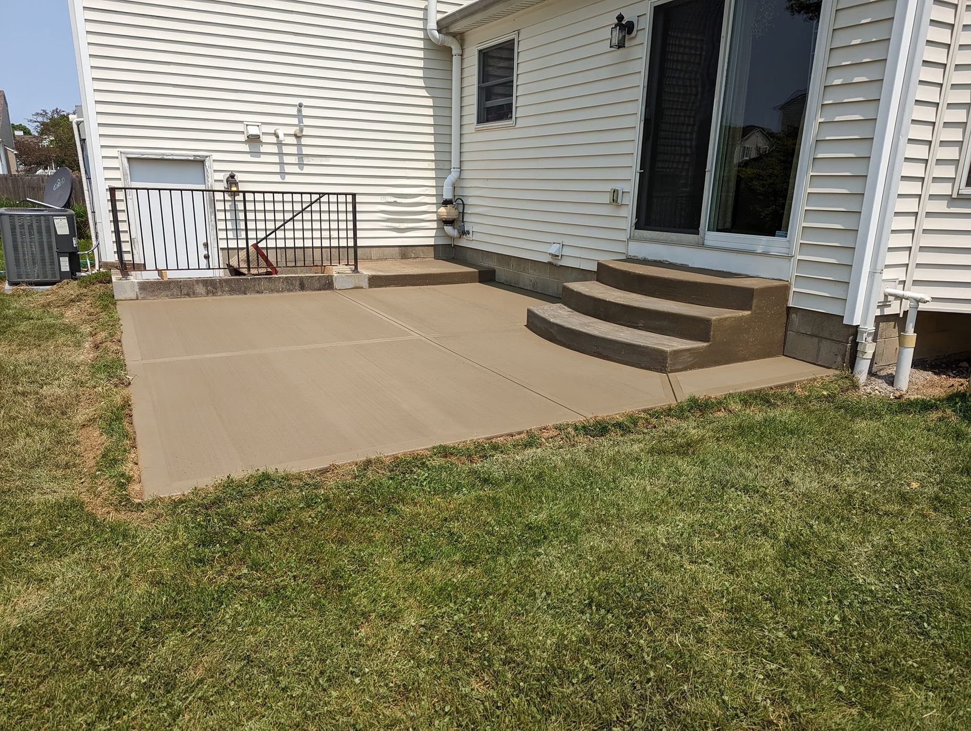 A patio with stairs and a railing in front of a house.