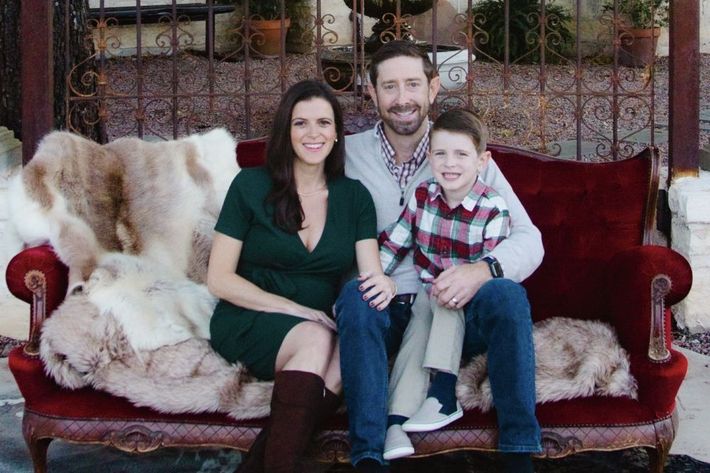 A family is posing for a picture while sitting on a red couch.