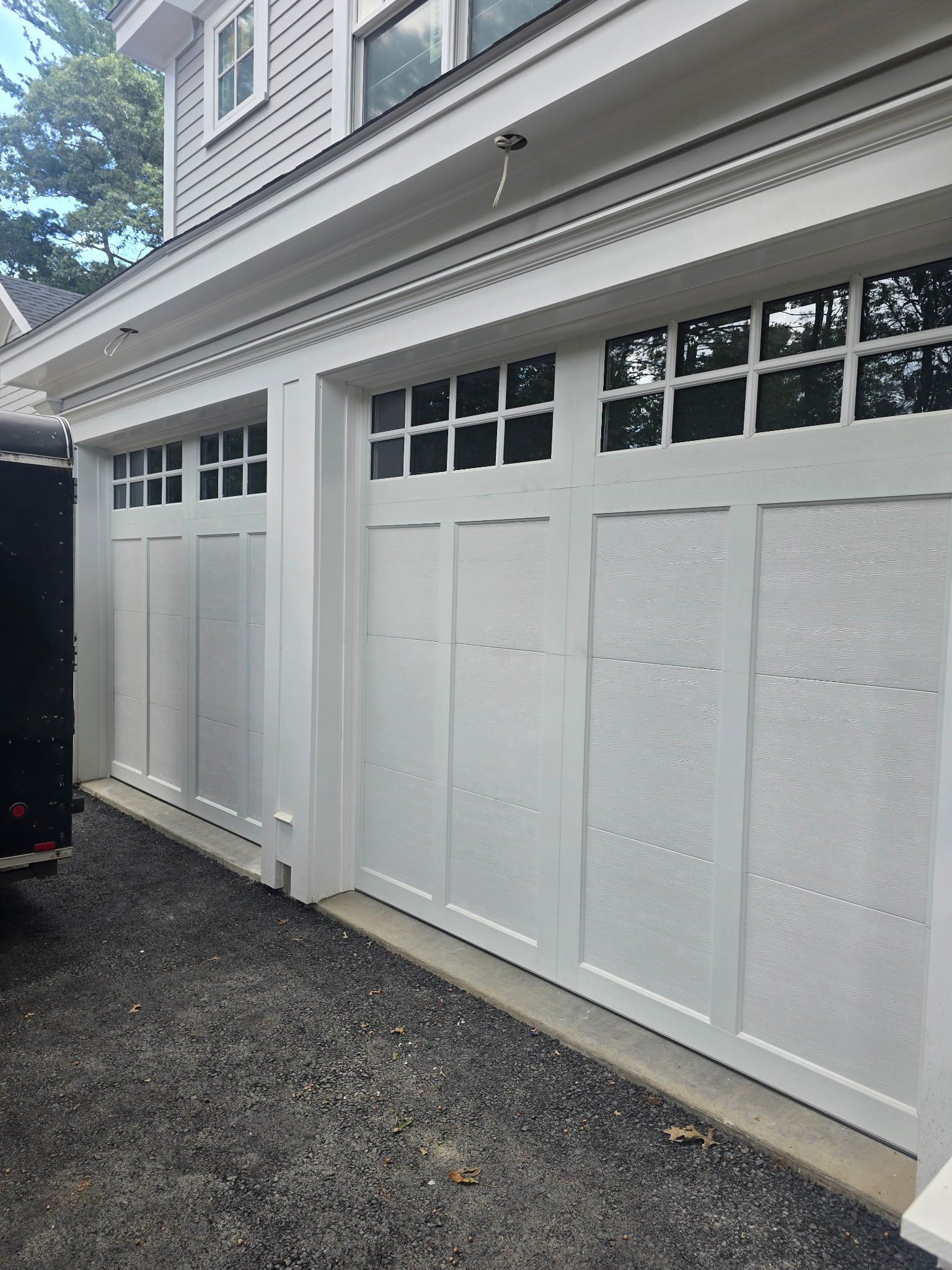 White garage doors with windows on a building with a gravel driveway.