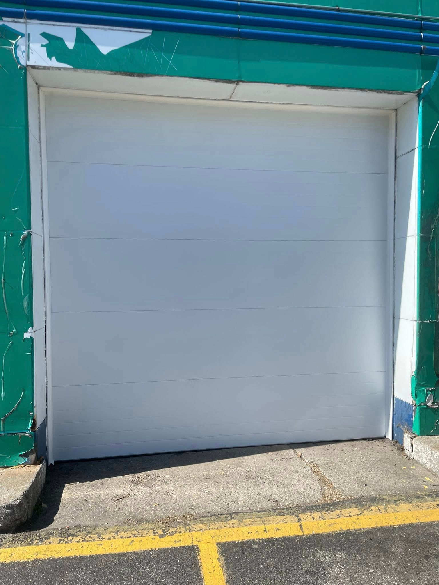White garage door with green trim and yellow lines on asphalt.