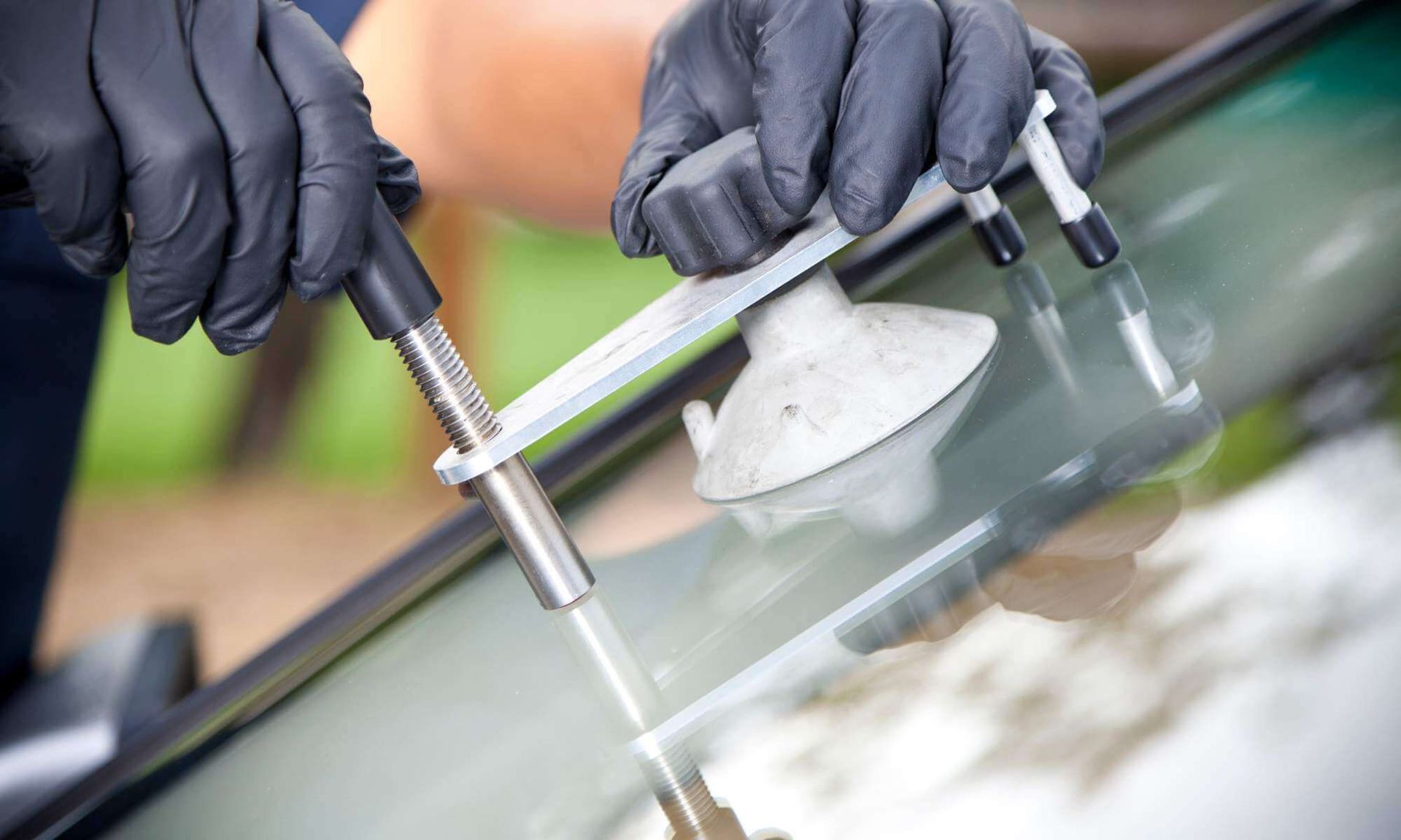 Gloved hands polishing a car windshield with a buffer tool