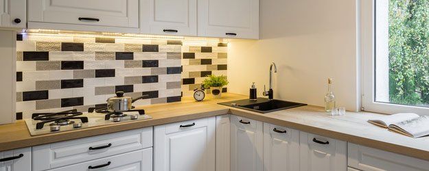 functional kitchen with classic white cabinets and window