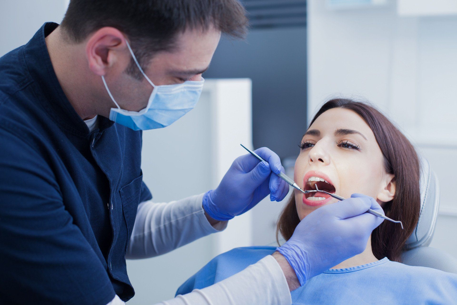 Dentist examining a patient's teeth with dental instruments; in a dental office.