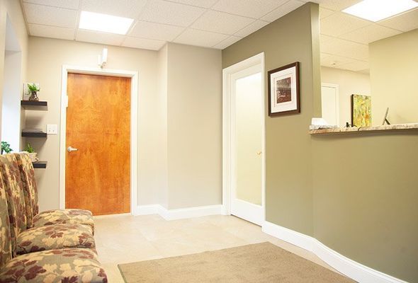 Waiting room with chairs, door, and reception desk. Neutral colors and natural light.