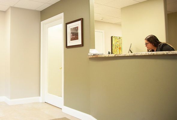 Reception area with person at counter. Olive green and beige walls, white door and trim.