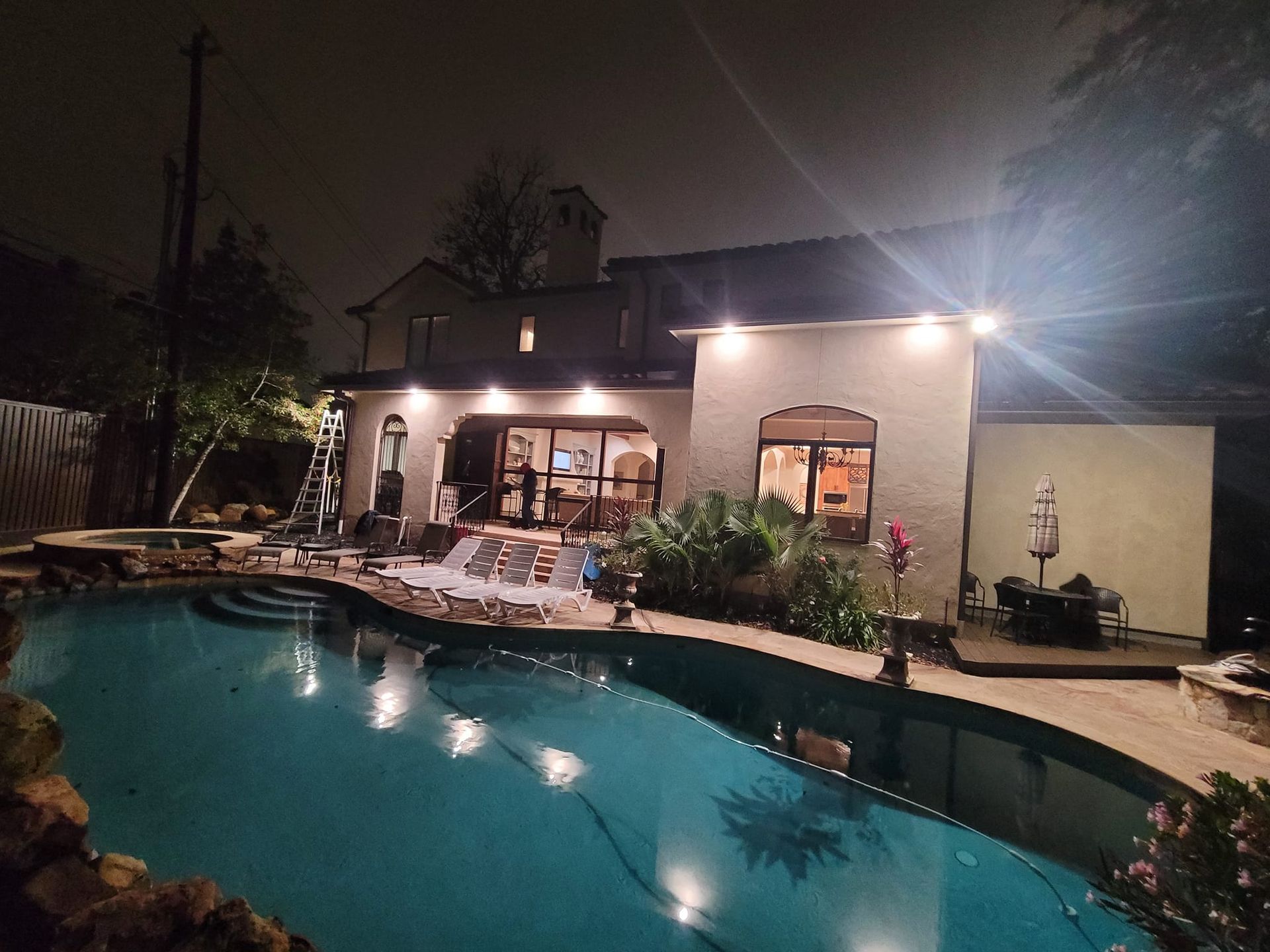A large house with a swimming pool in front of it at night