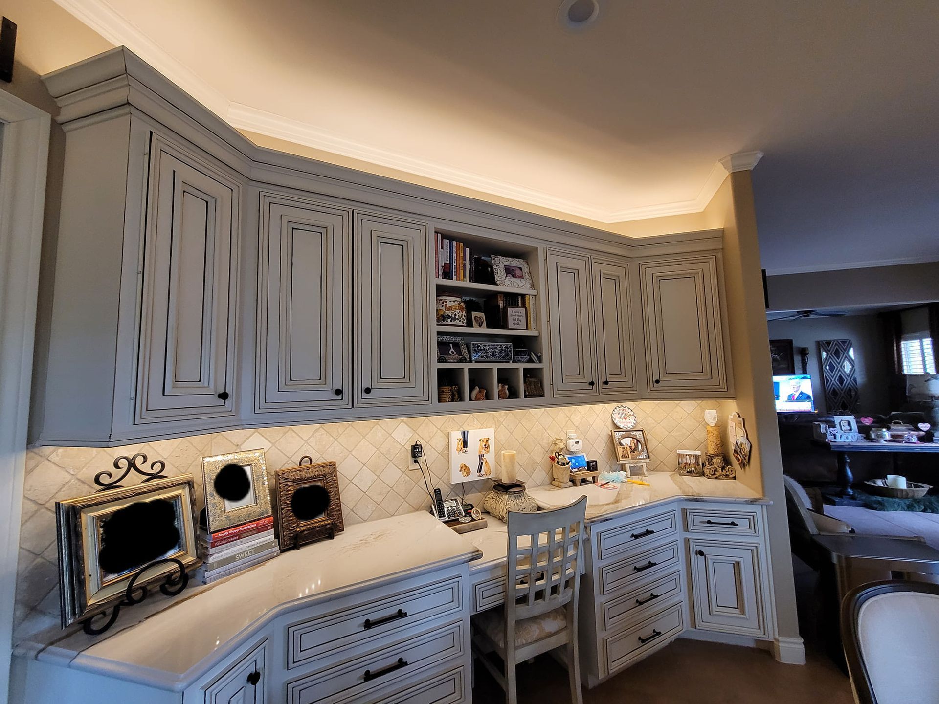 A kitchen with white cabinets and a desk with a chair.