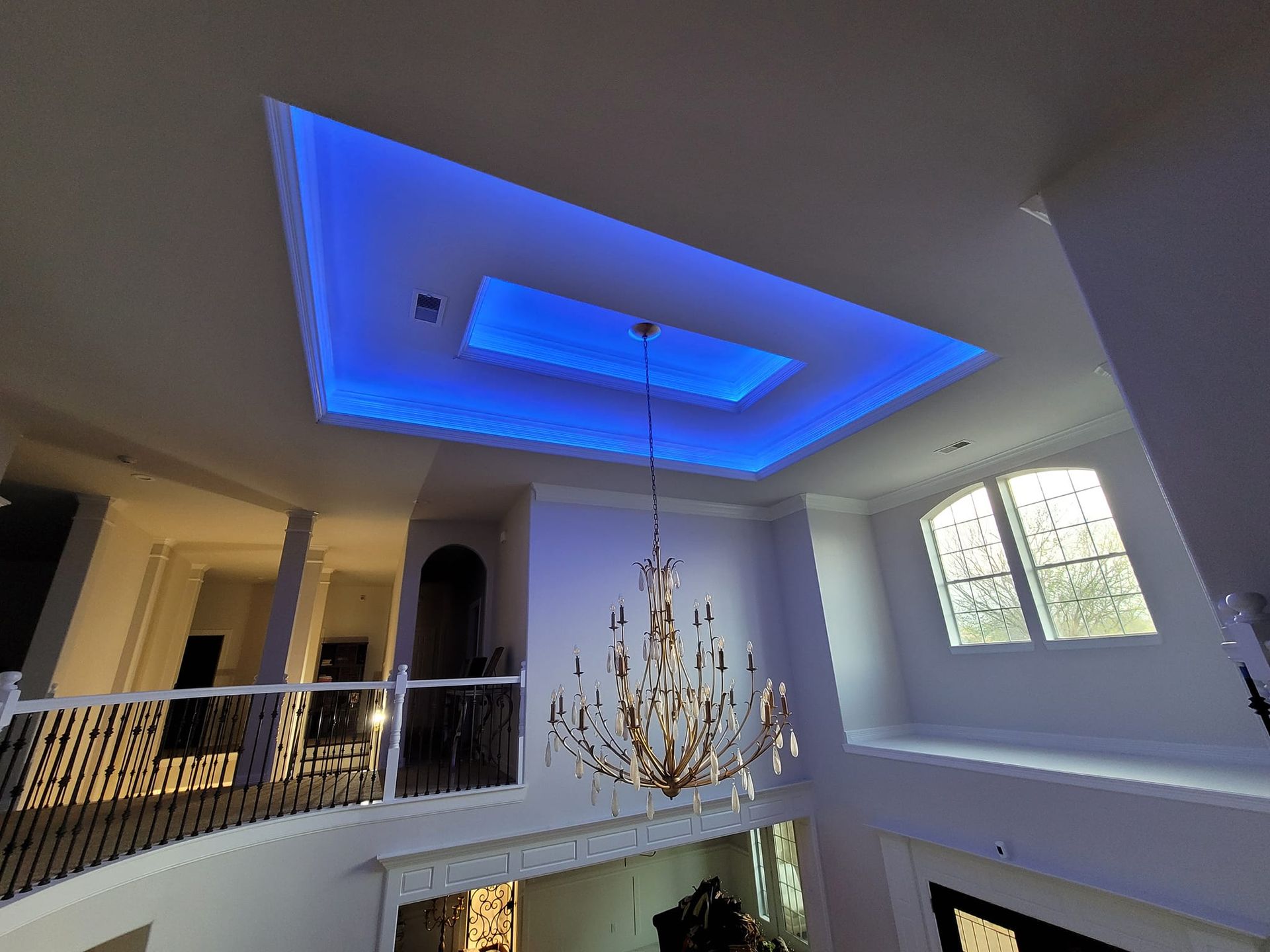A large room with a chandelier and a blue light on the ceiling.