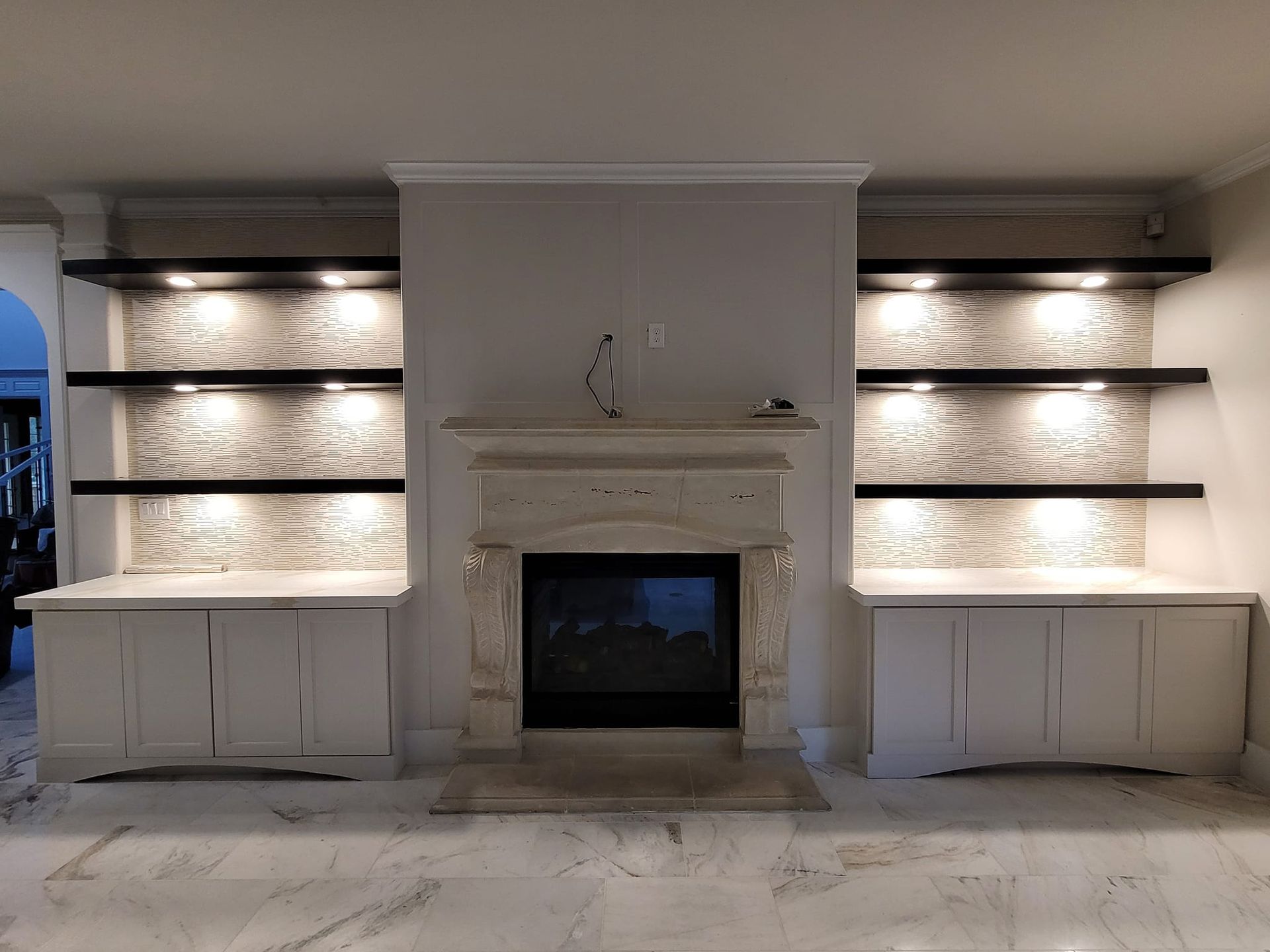 A living room with a fireplace , shelves and cabinets.