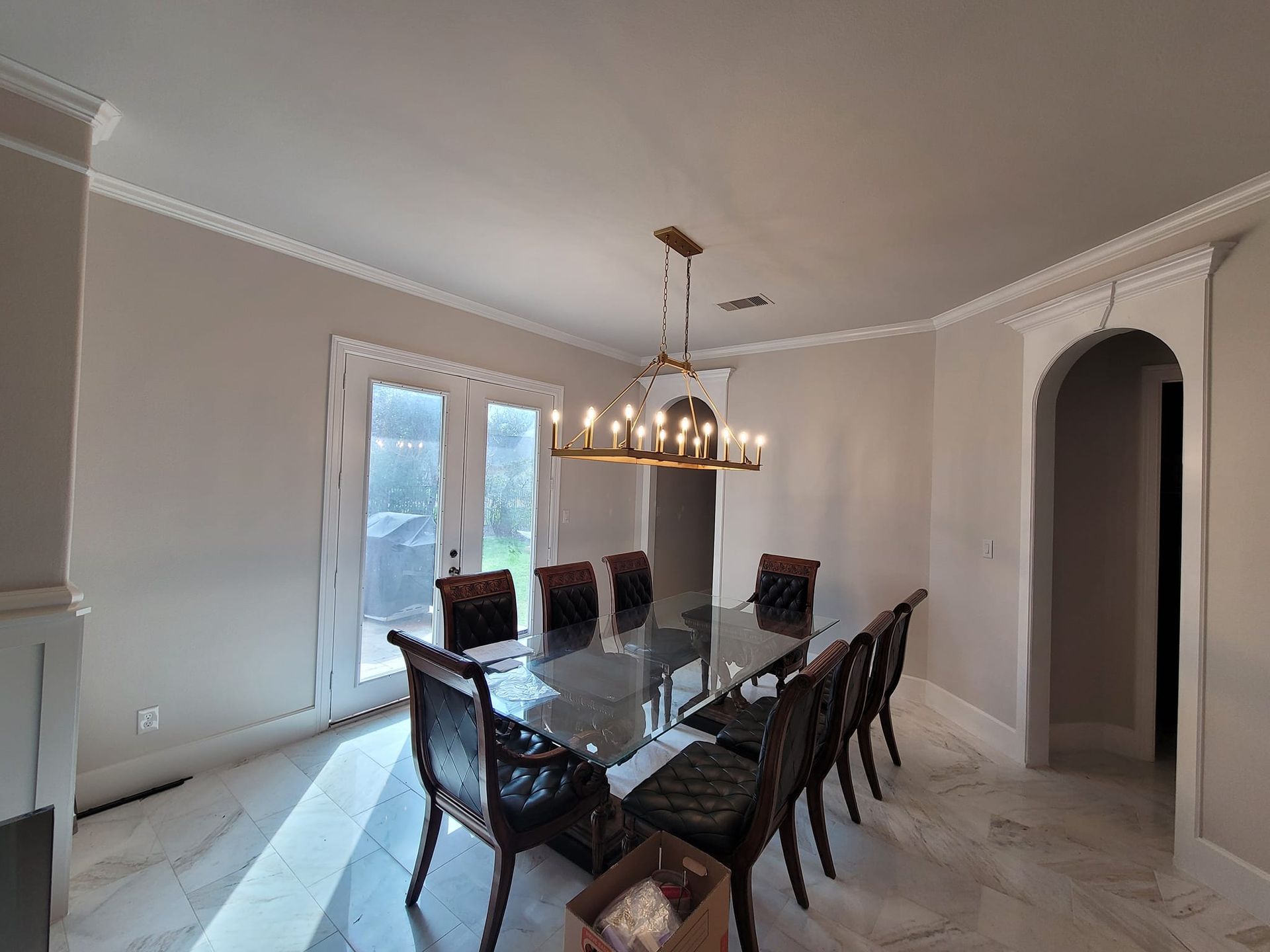 A dining room with a long table and chairs and a chandelier hanging from the ceiling.