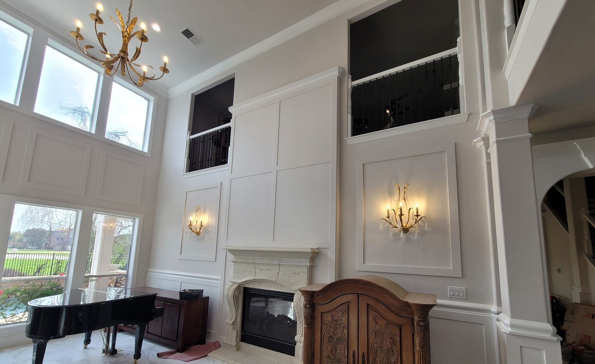A living room with a piano , fireplace , and chandelier.