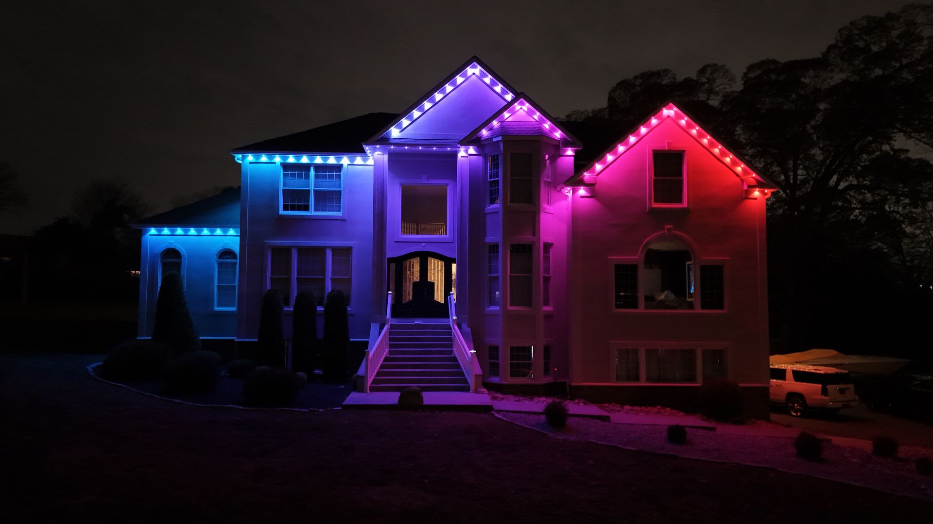 House lit with blue, purple, and pink lights at night