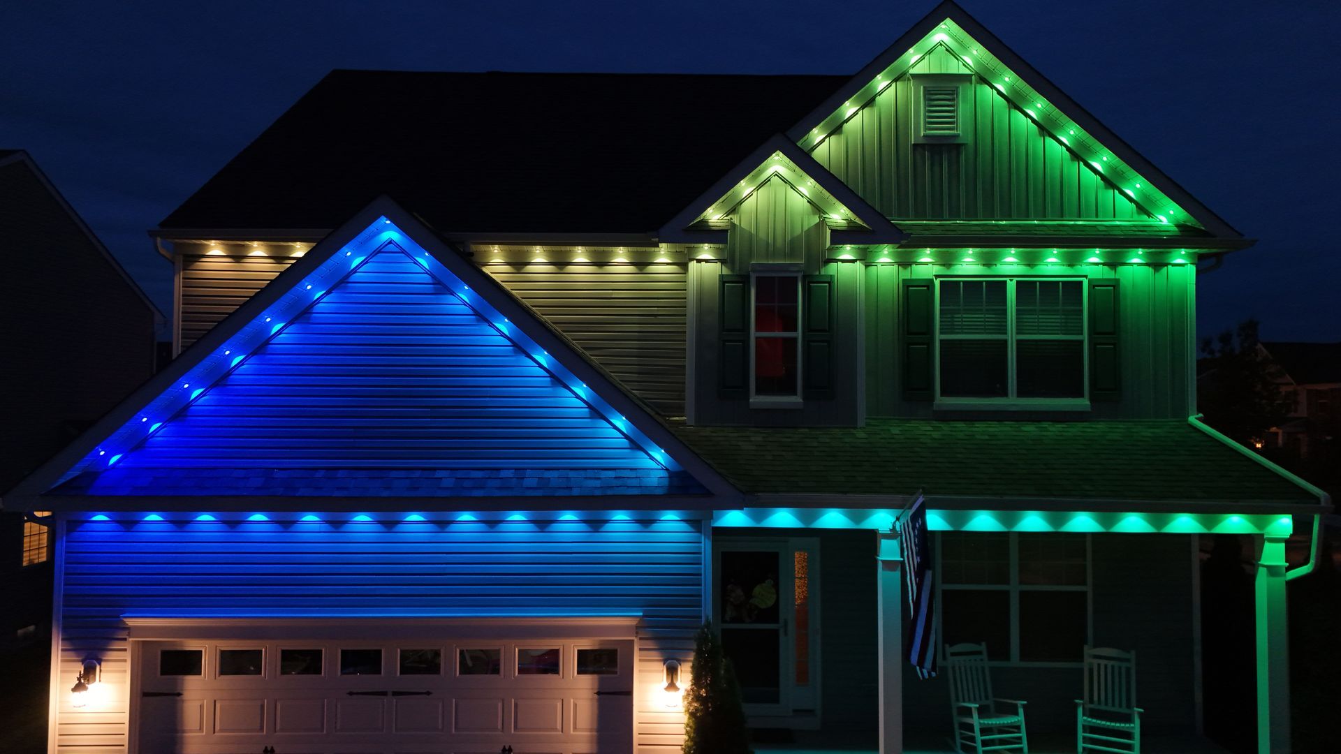 House lit with blue and green holiday lights at night