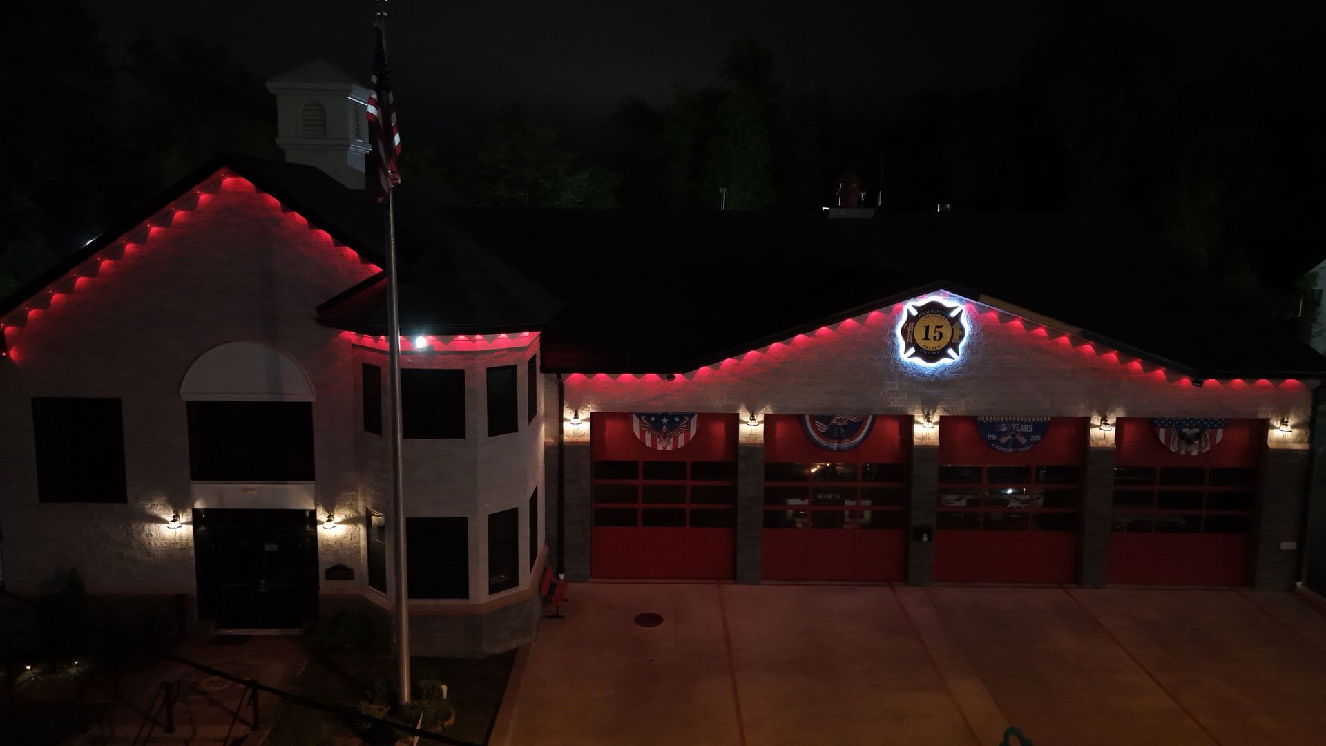 House at night with red holiday lights along the roof and a lit garage front