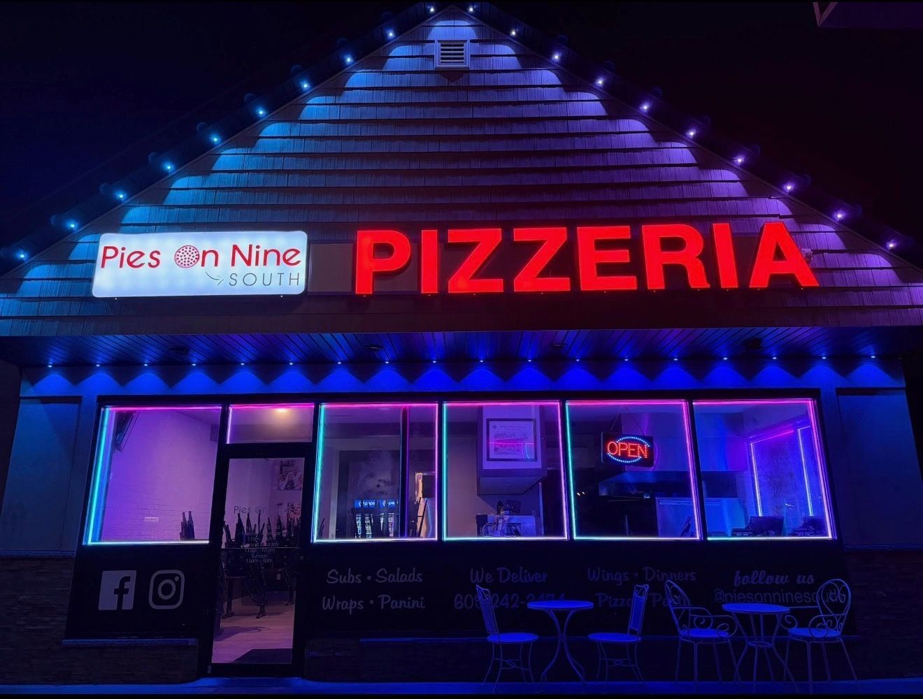 Neon-lit pizzeria storefront at night with a bright red sign and purple-blue lighting.