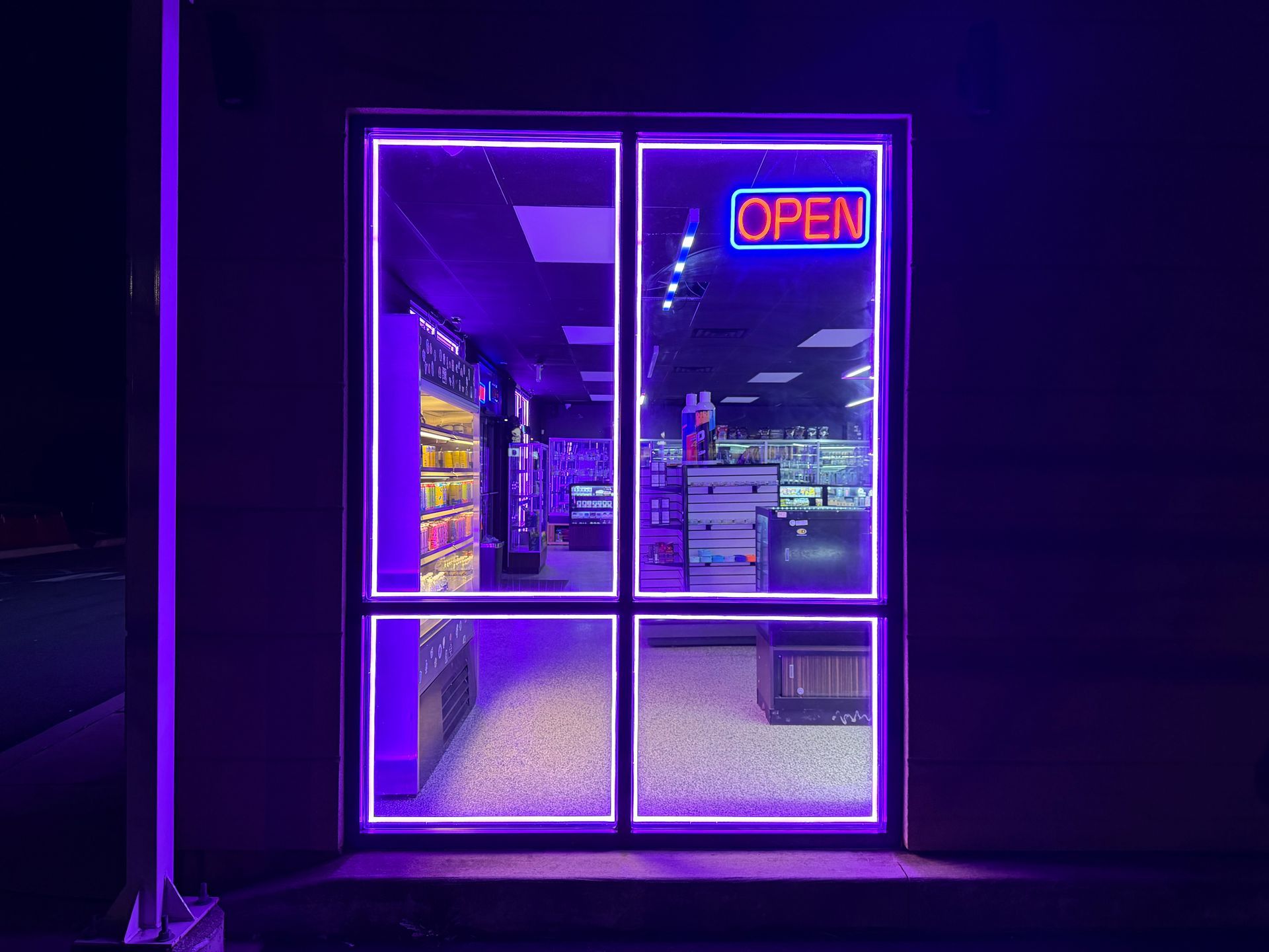 Neon-lit storefront entrance with glowing purple frame and an OPEN sign at night