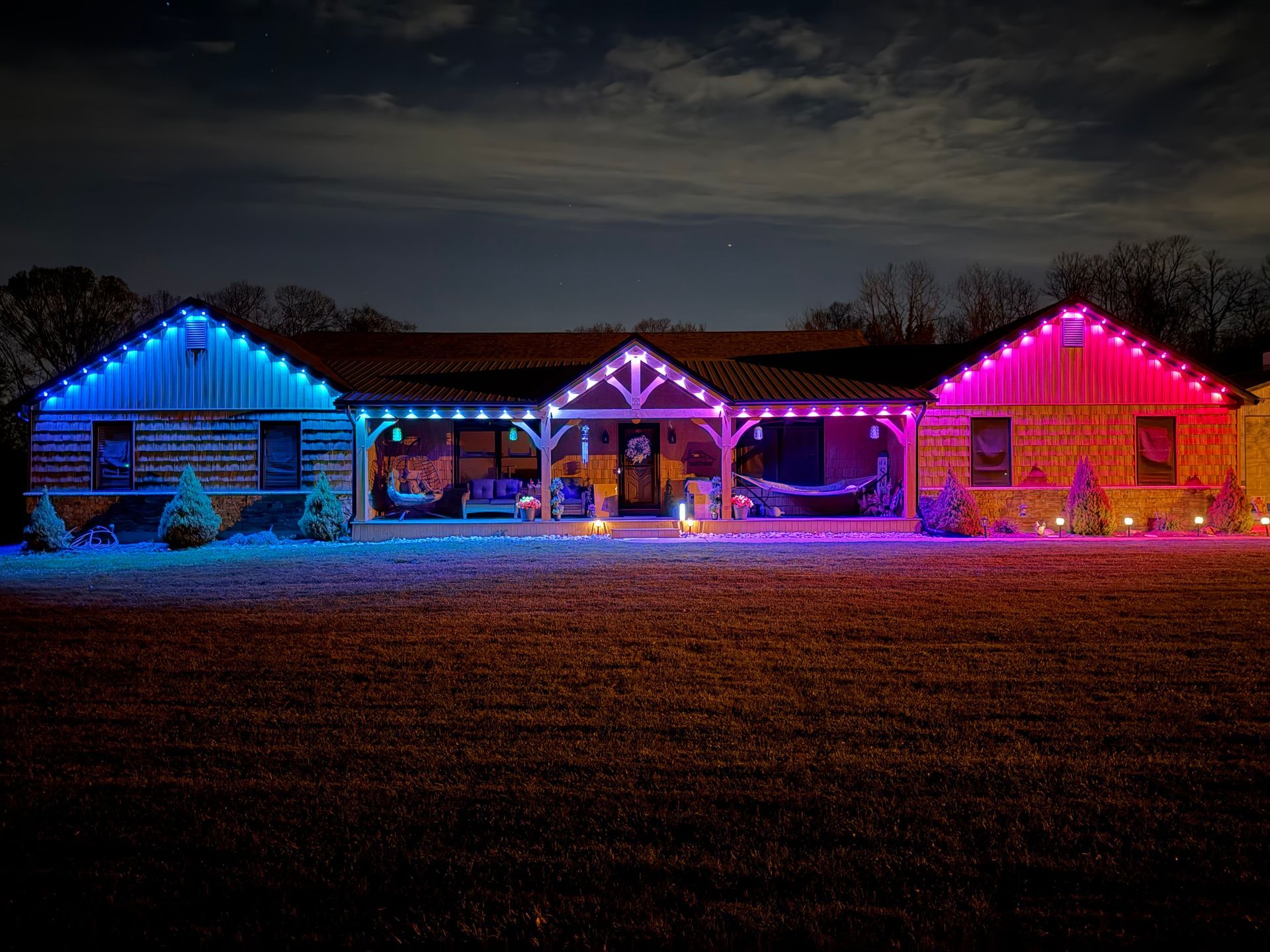 House outlined in blue, purple, and pink holiday lights at night