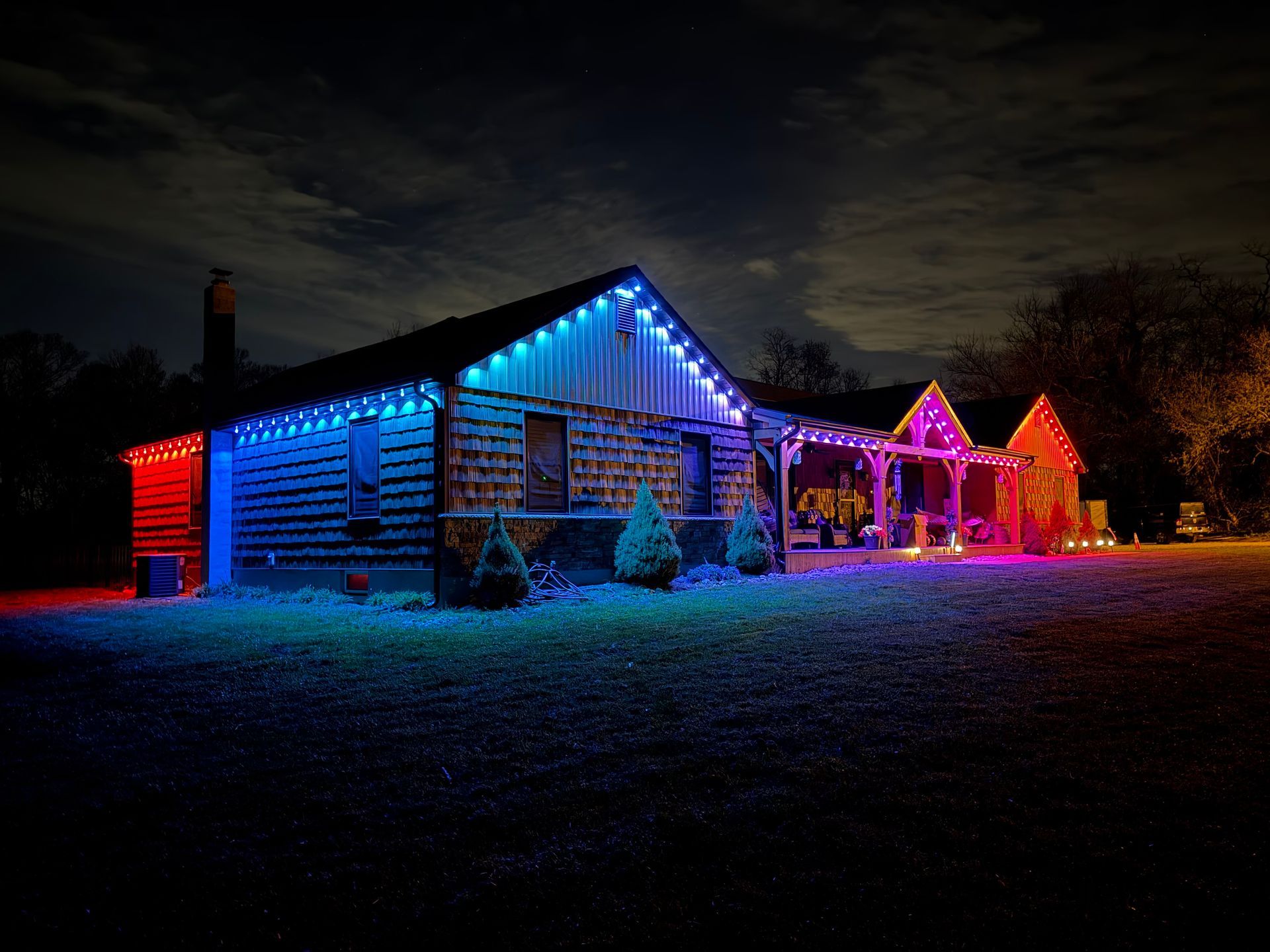 House with colorful blue, red, and pink holiday lights glowing at night