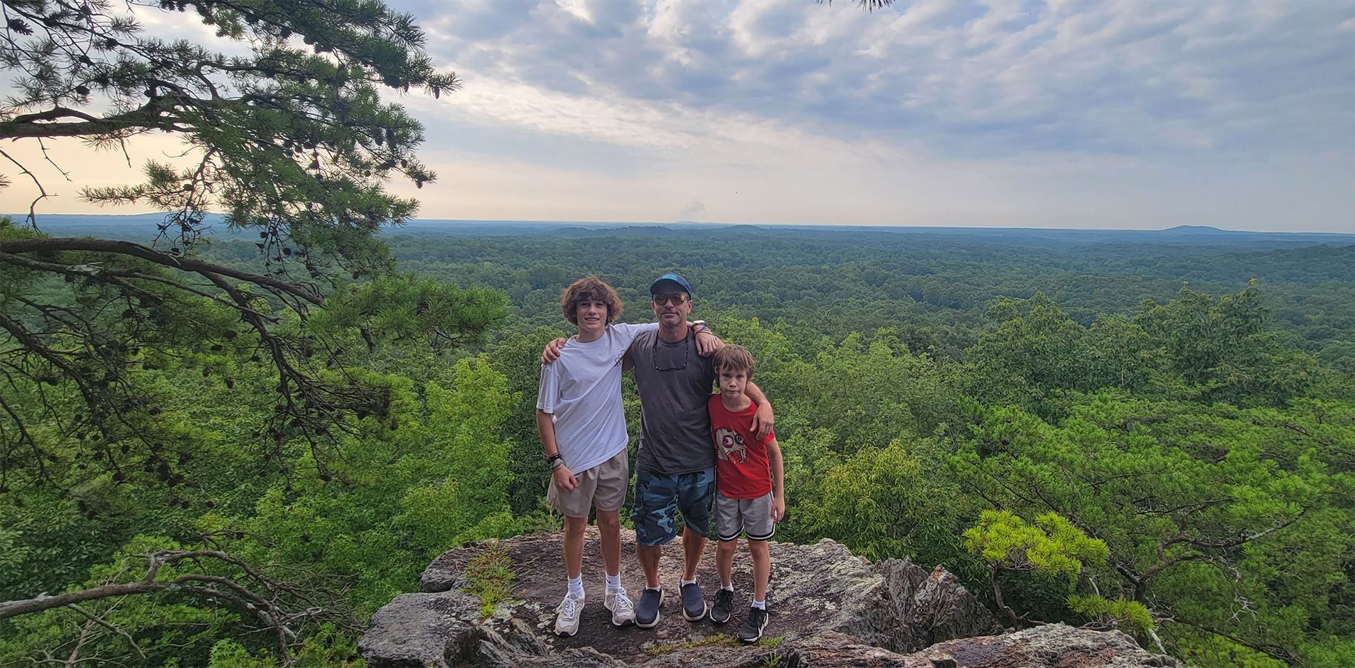 A man and two children are standing on top of a mountain.