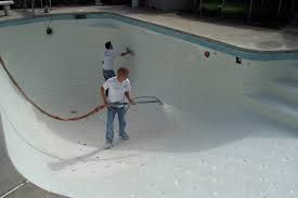 A man is cleaning a swimming pool with a hose.
