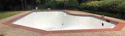 A large white swimming pool with a brick border in a backyard.