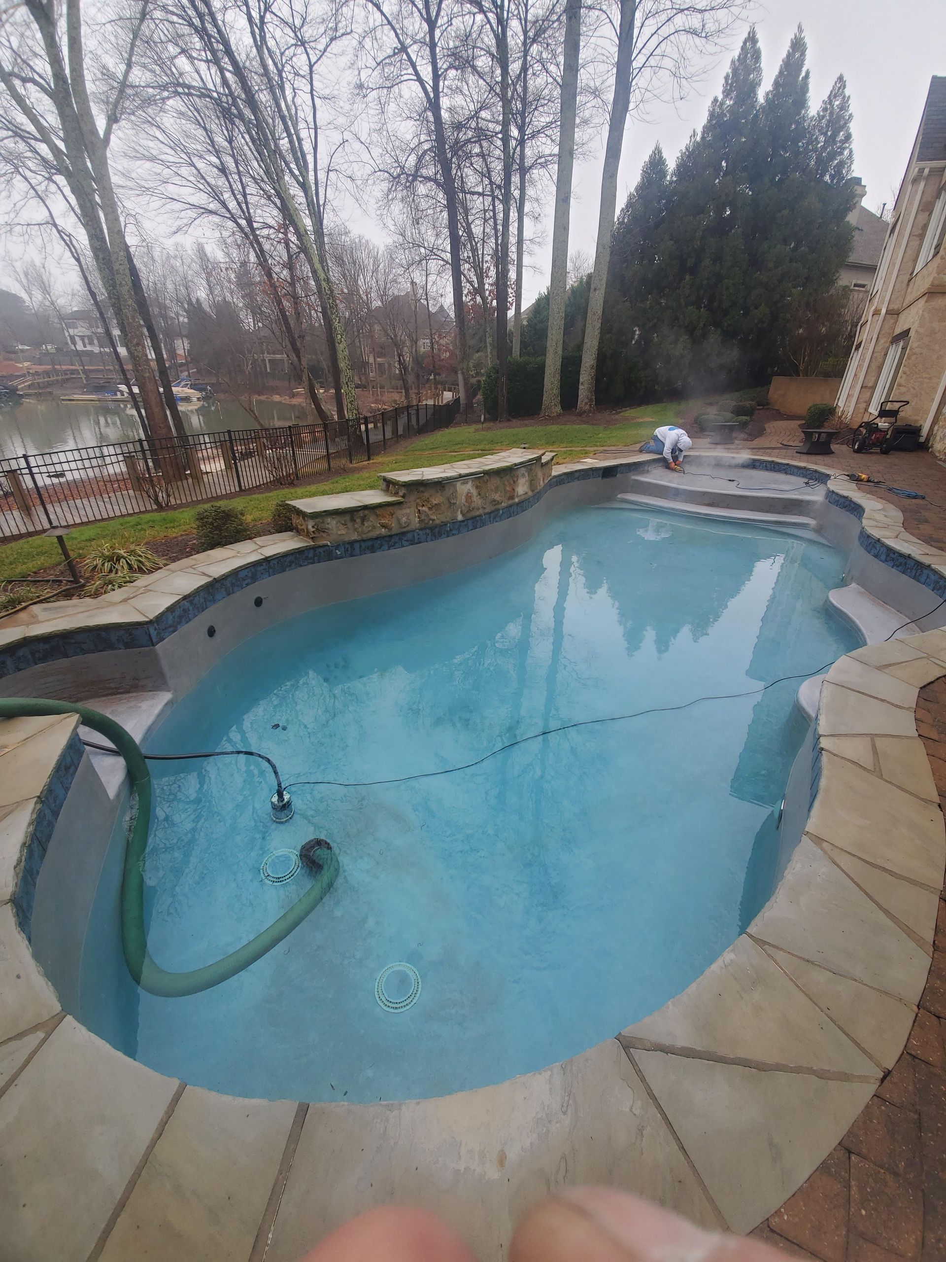 A swimming pool with a hose attached to it and trees in the background.
