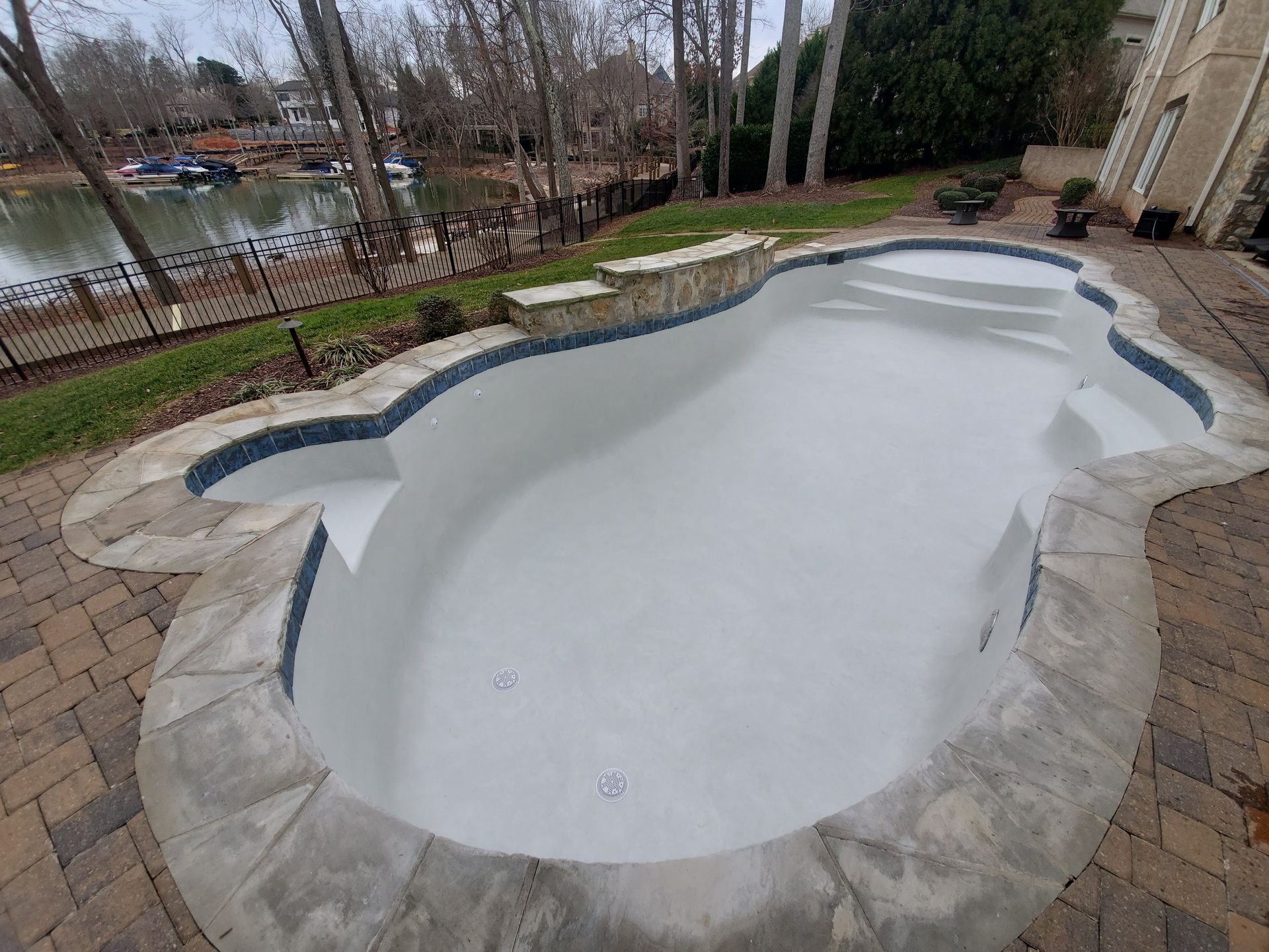 A large white swimming pool is sitting on top of a brick patio.