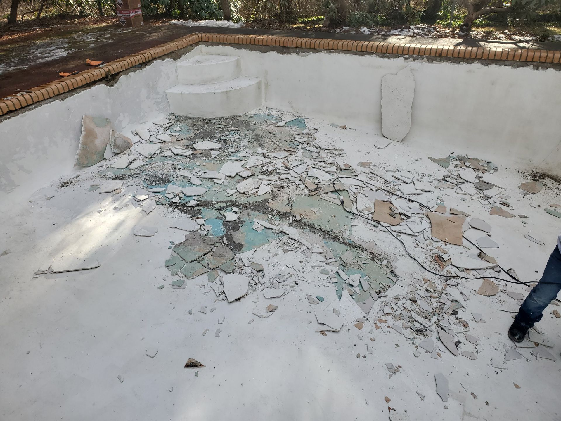 A swimming pool with a lot of broken glass on the floor.