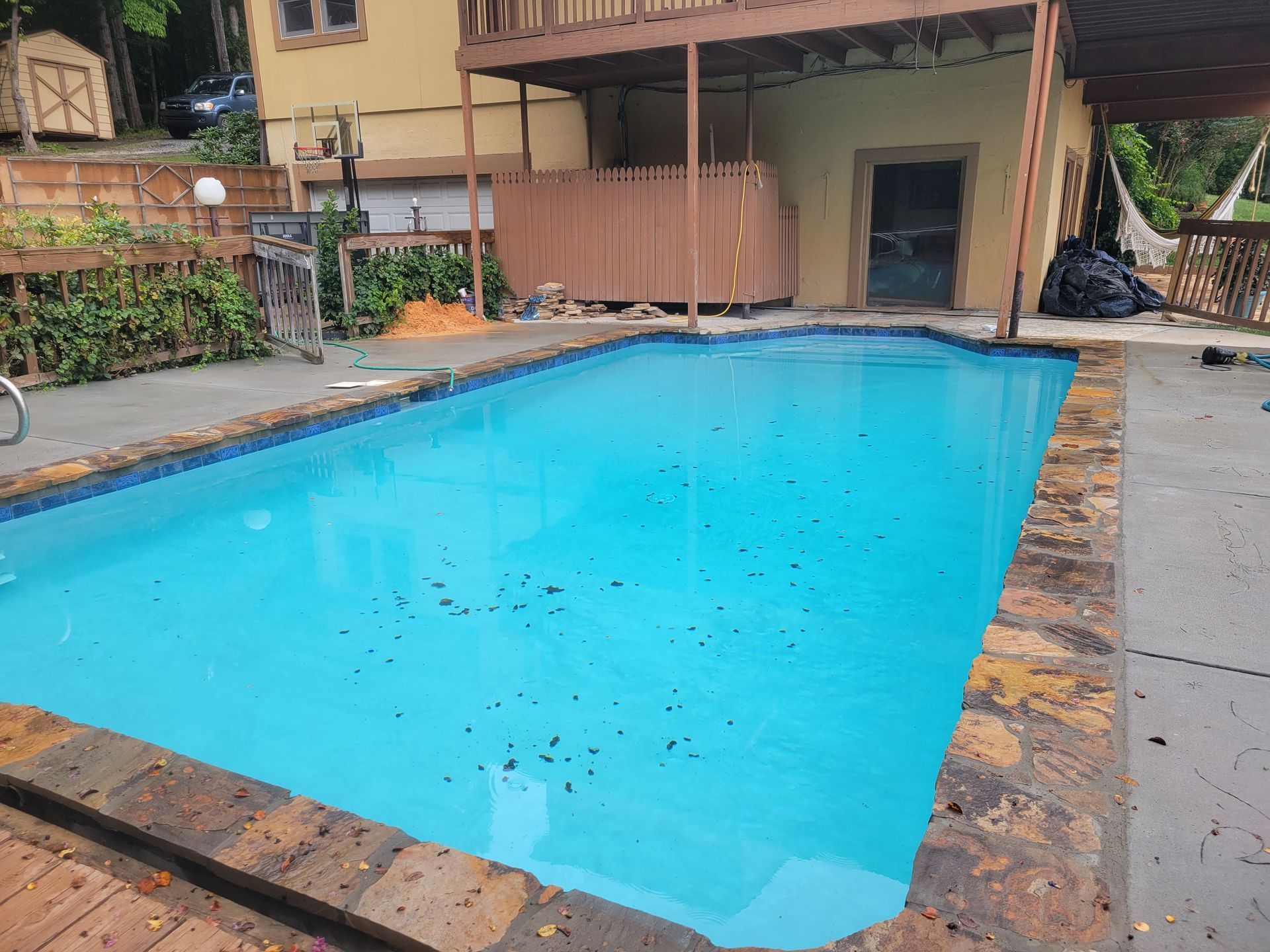 There is a large swimming pool in the backyard of a house.