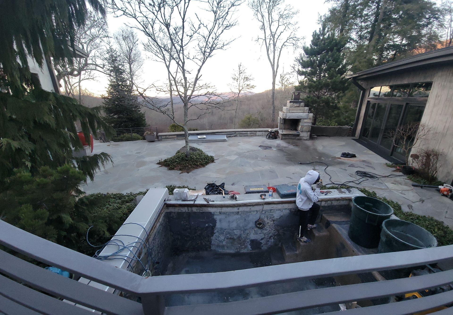 A man is working on a swimming pool in a backyard.