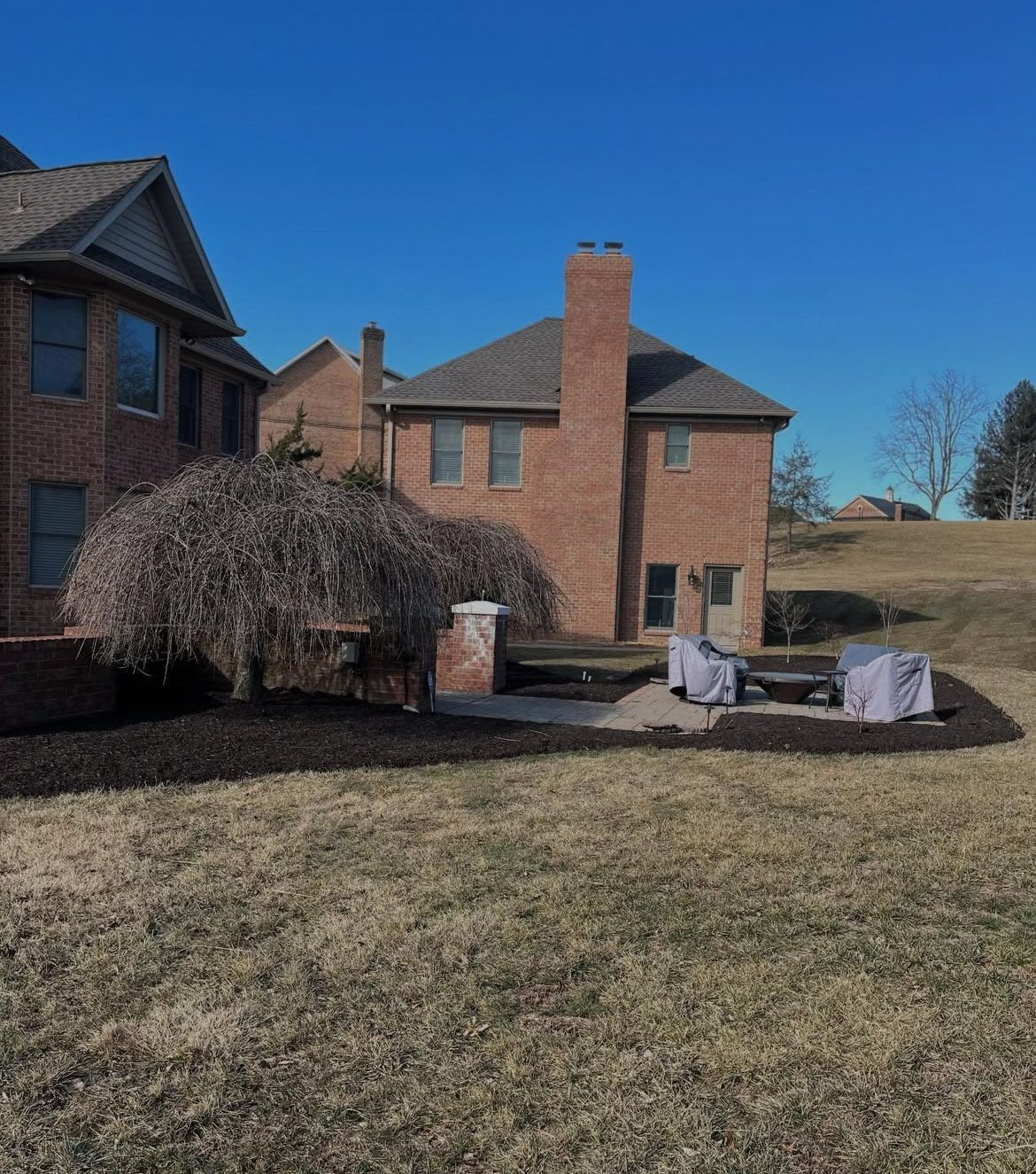 A large brick house with a chimney in the backyard.