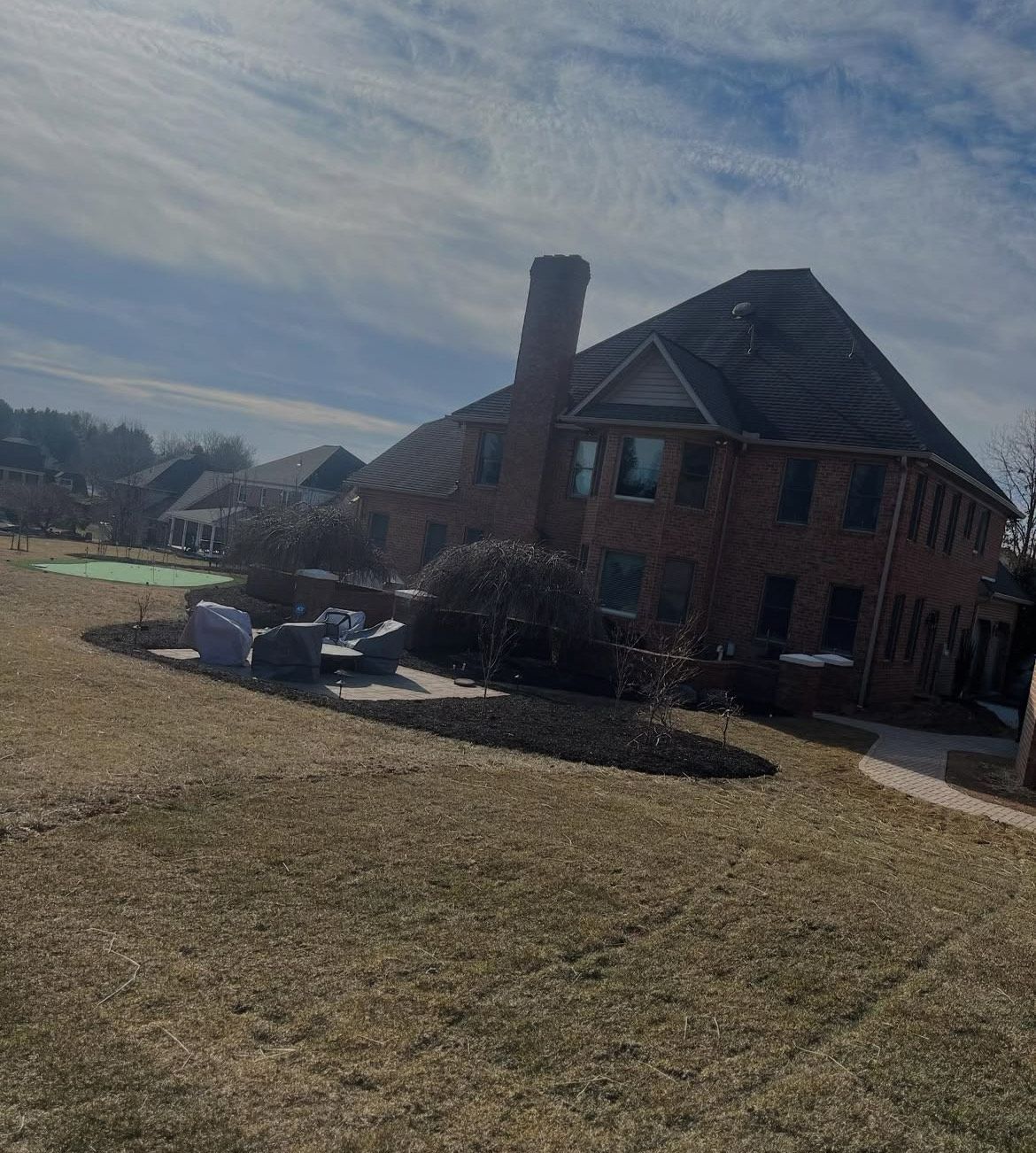 A large brick house is sitting in the middle of a grassy field.