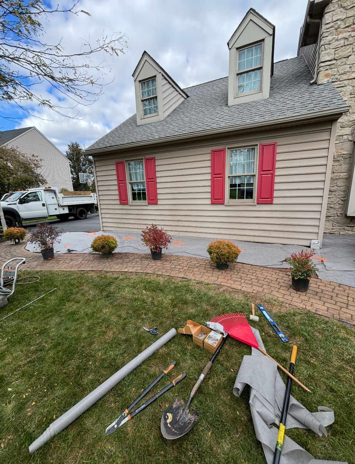 A house with red shutters and a lot of tools in front of it.