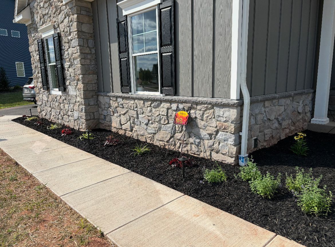 A house with a stone facade and a sidewalk in front of it.