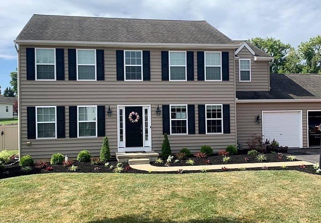 A large house with black shutters and a wreath on the door.