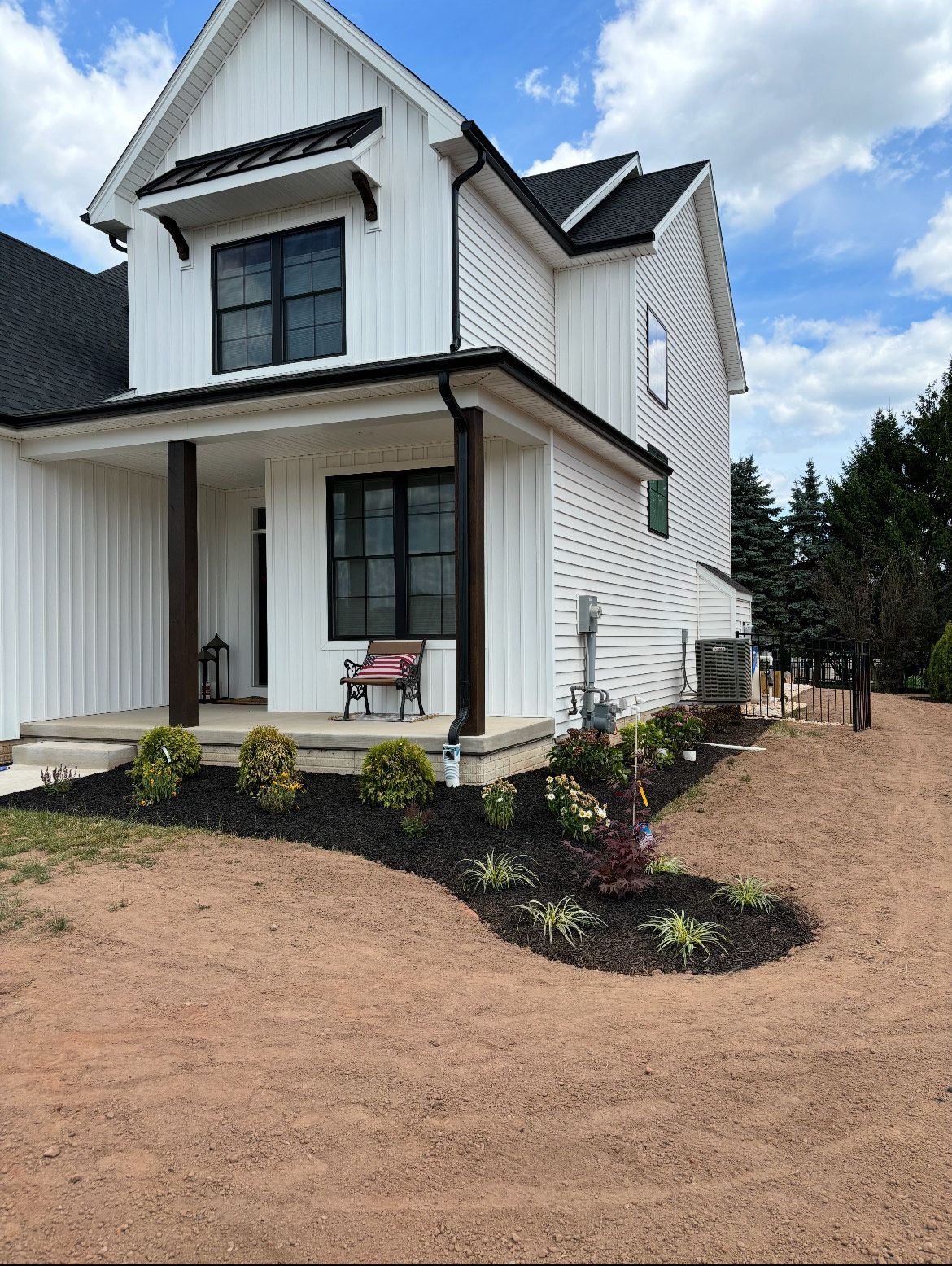 A white house with a black roof and a large porch.