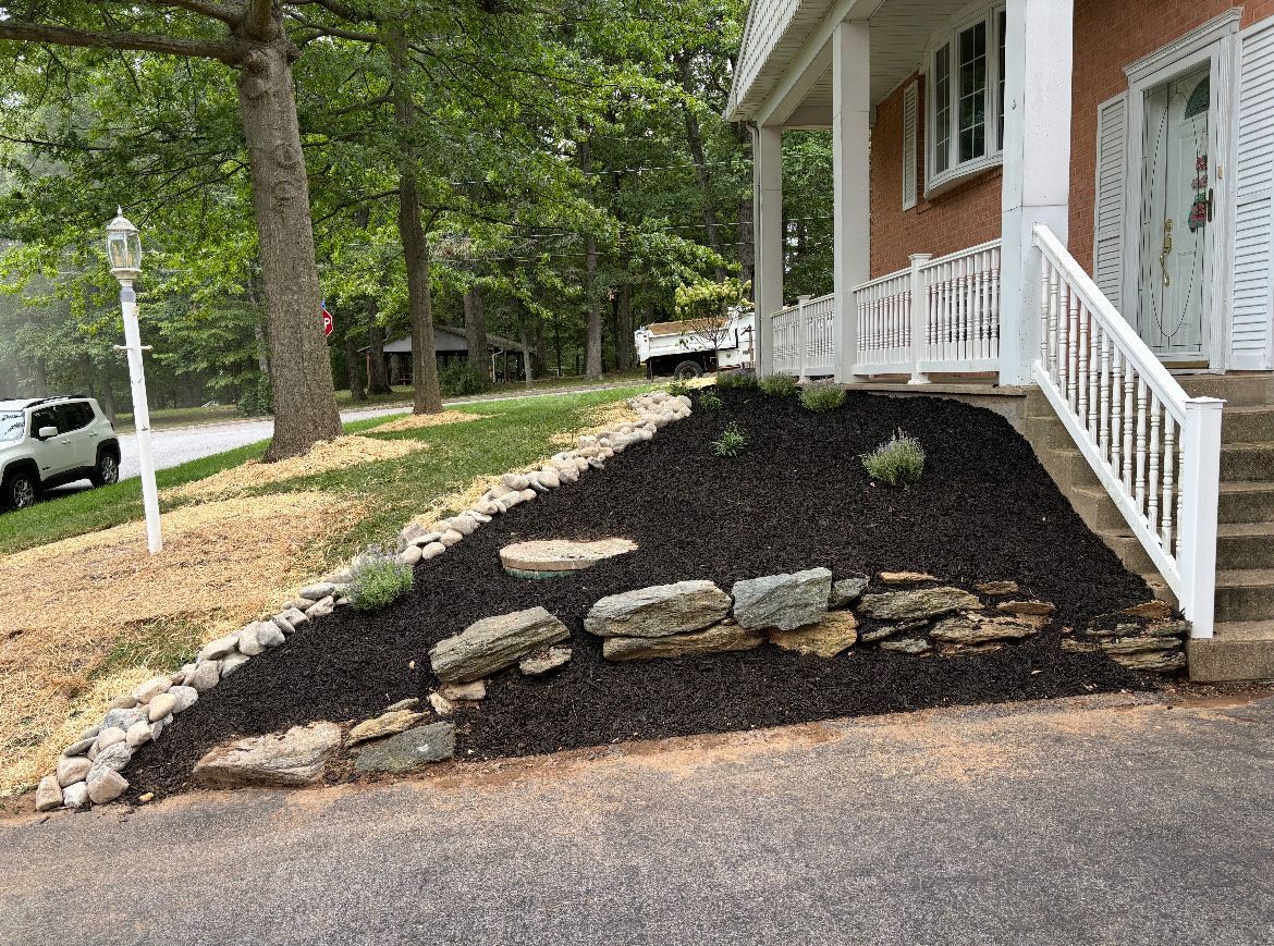 A house with stairs and a rock wall in front of it.