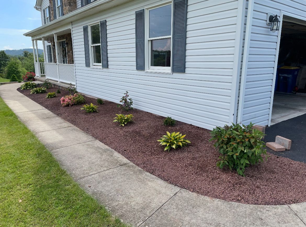 A white house with a lot of plants in front of it.