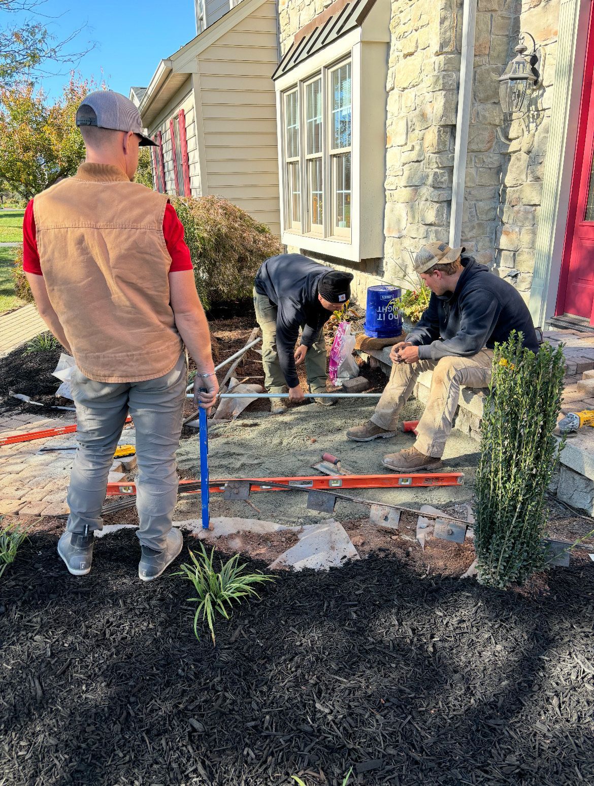 A group of men are working on a landscaping project in front of a house.