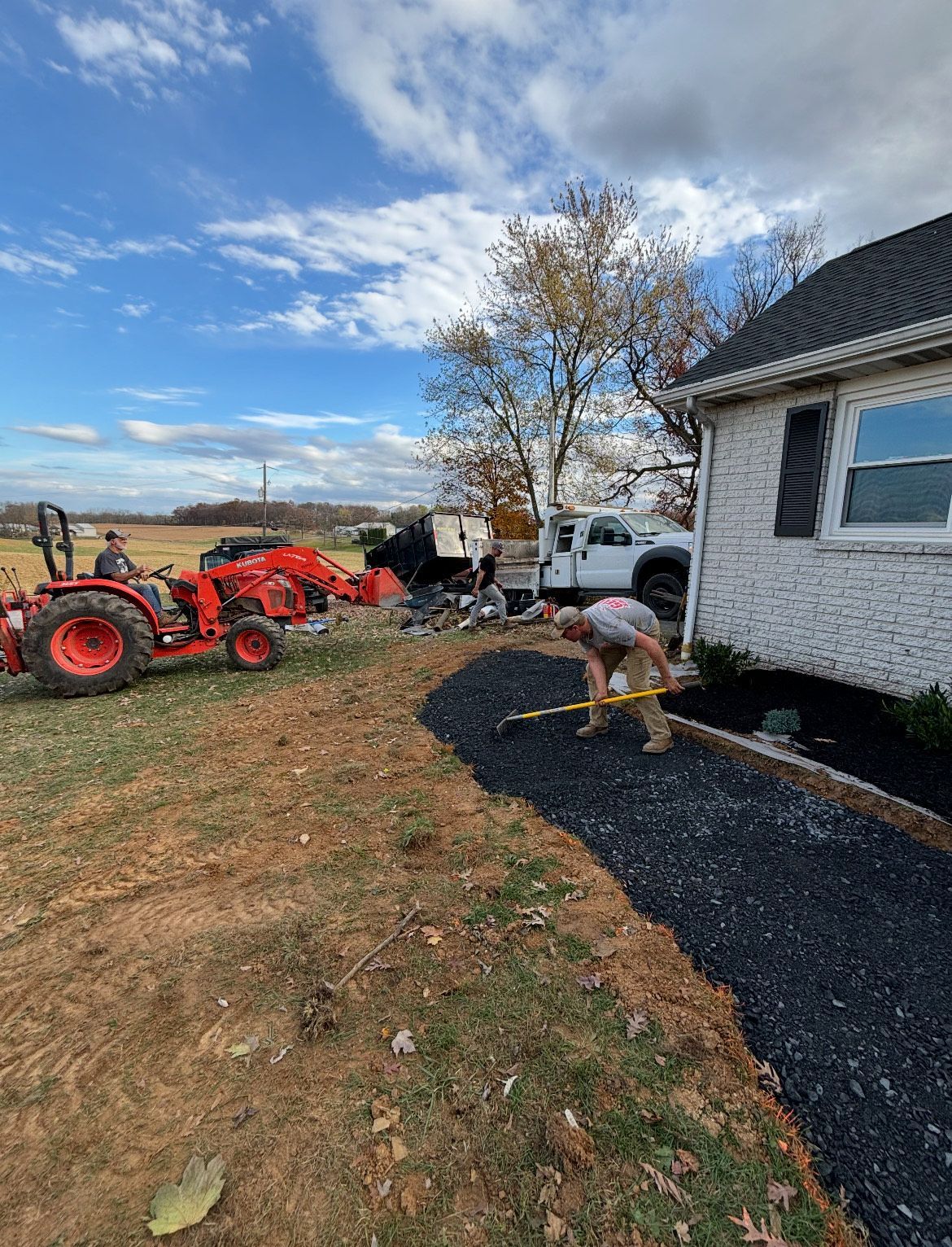 A man is working on a driveway in front of a house.